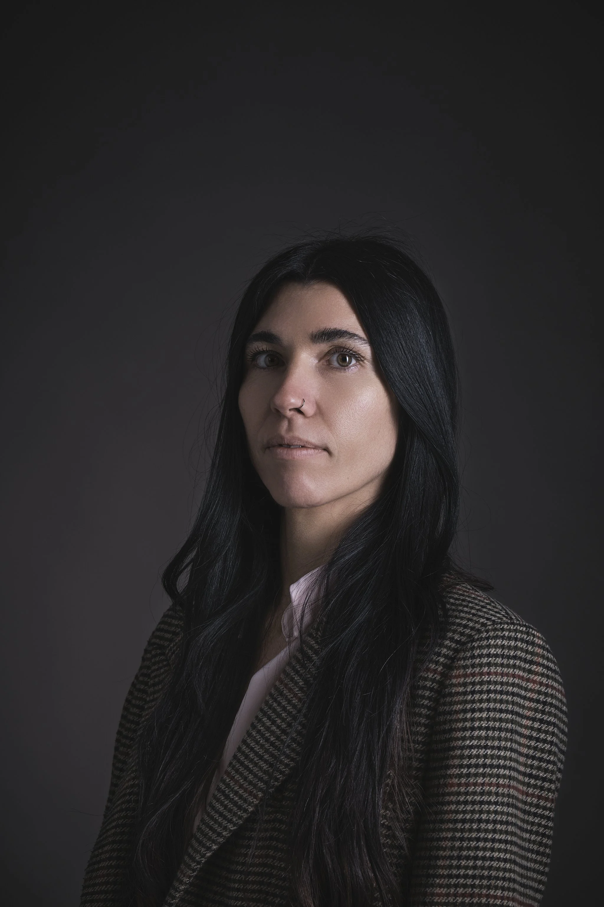 Ragazza con capelli ricci e un vestito nero si trova di fronte a uno sfondo giallo.