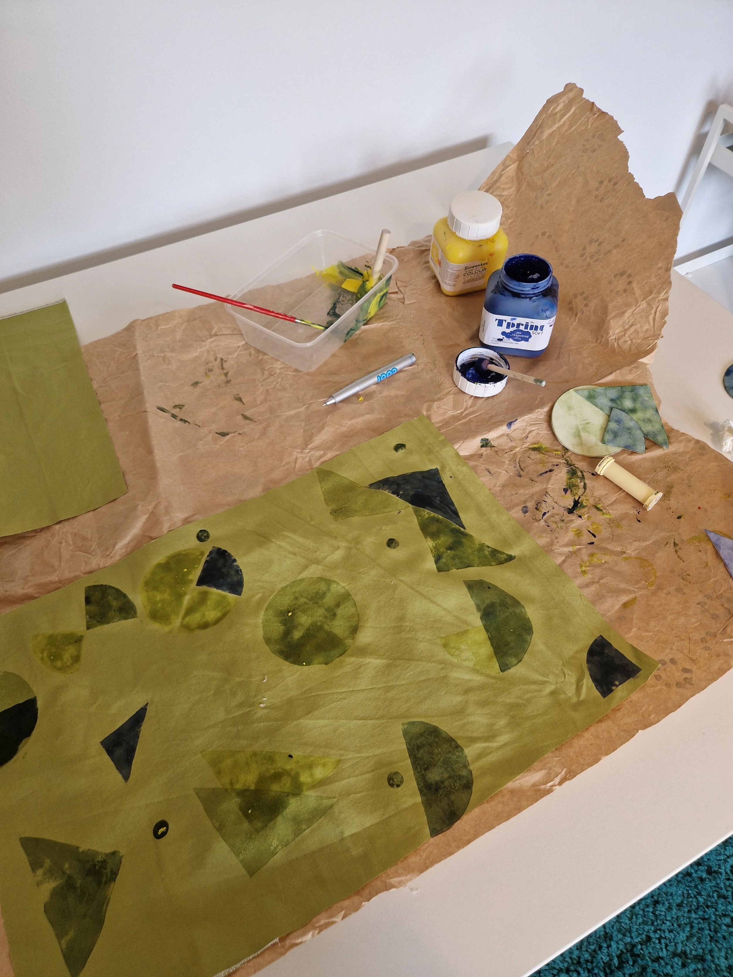 Art project workspace with paper, paints, brushes, and tools on a table.