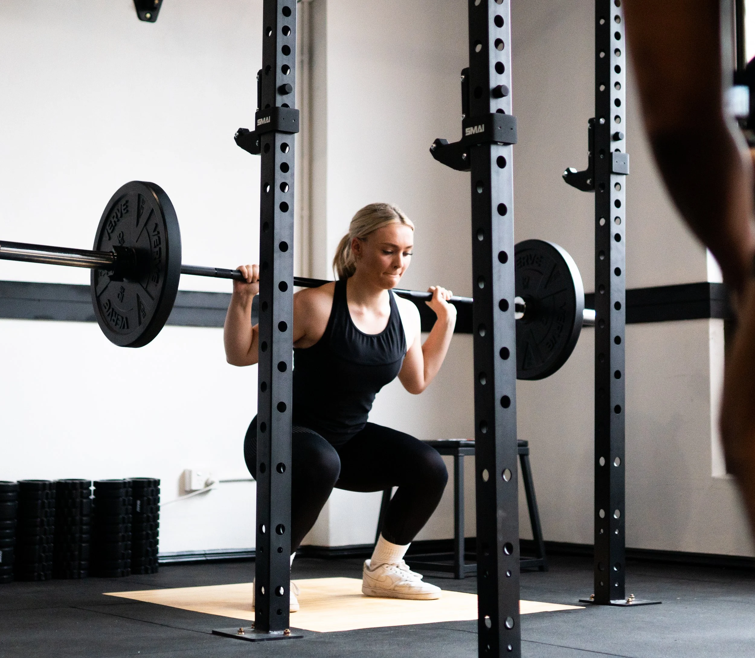 Woman performing a squat exercise with a barbell in gym