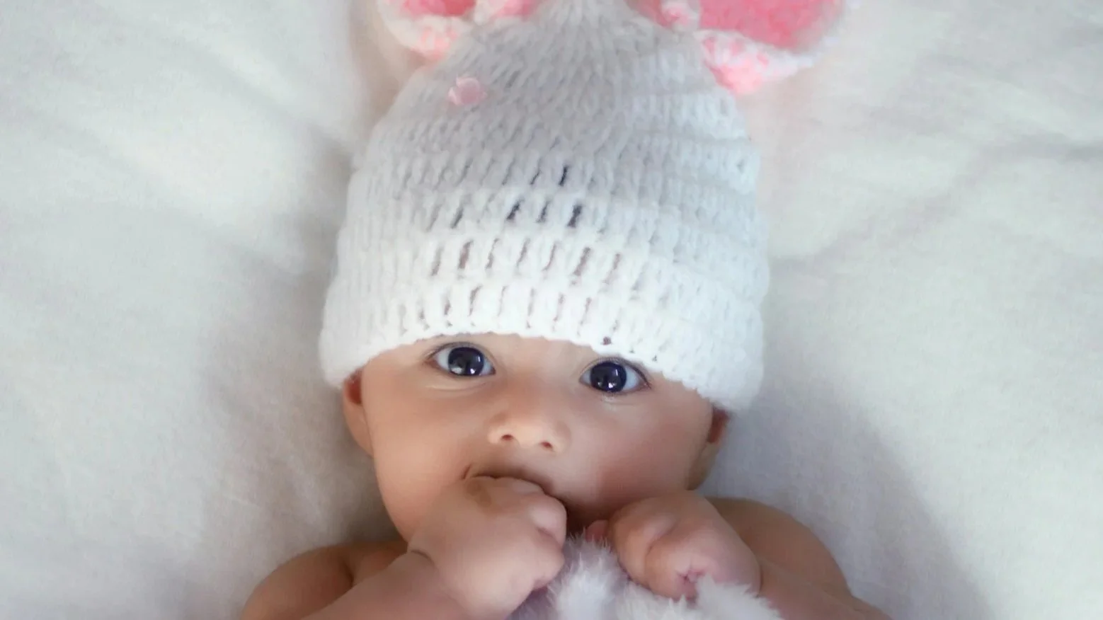 Ein baby mit Wollmütze schaut in die Kamera