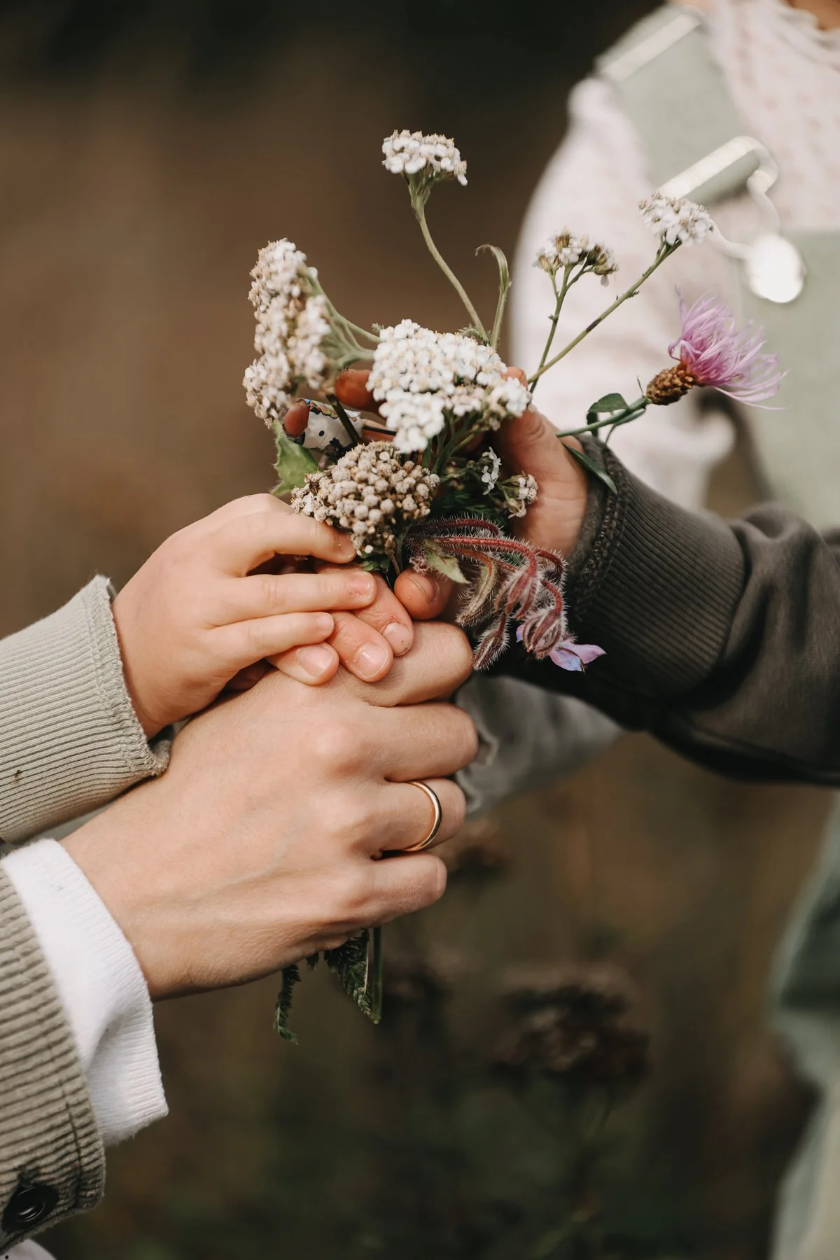 Zwei Personen tauschen ein Blumenstrauß aus, einer hält ihn mit einer Hand, die andere mit beiden Händen, im Hintergrund verschwommen.