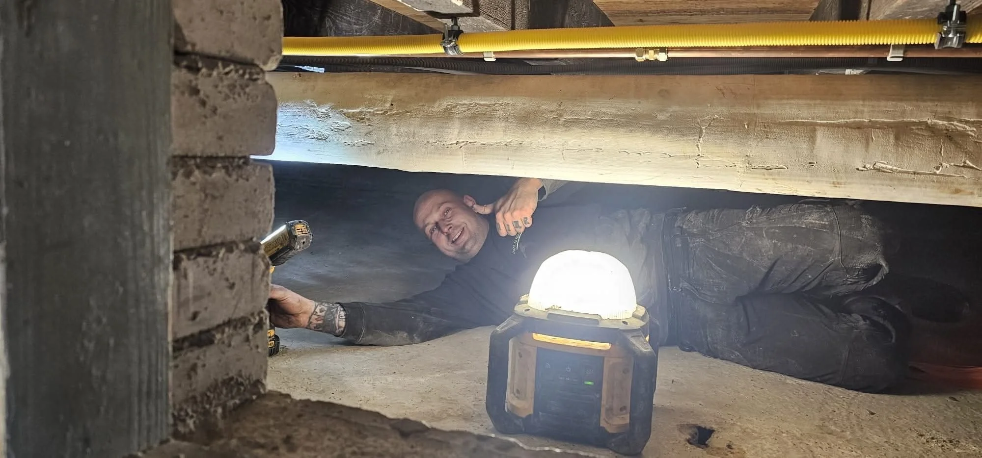 Monteur inspecteert en repareert het riool in de kruipruimte onder de vloer