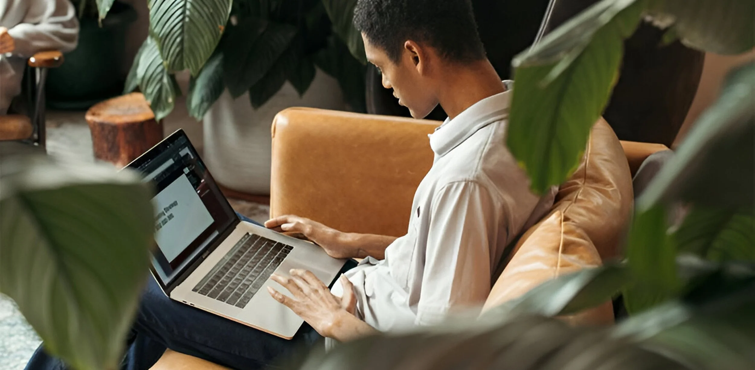A man working at a laptop on a sofa