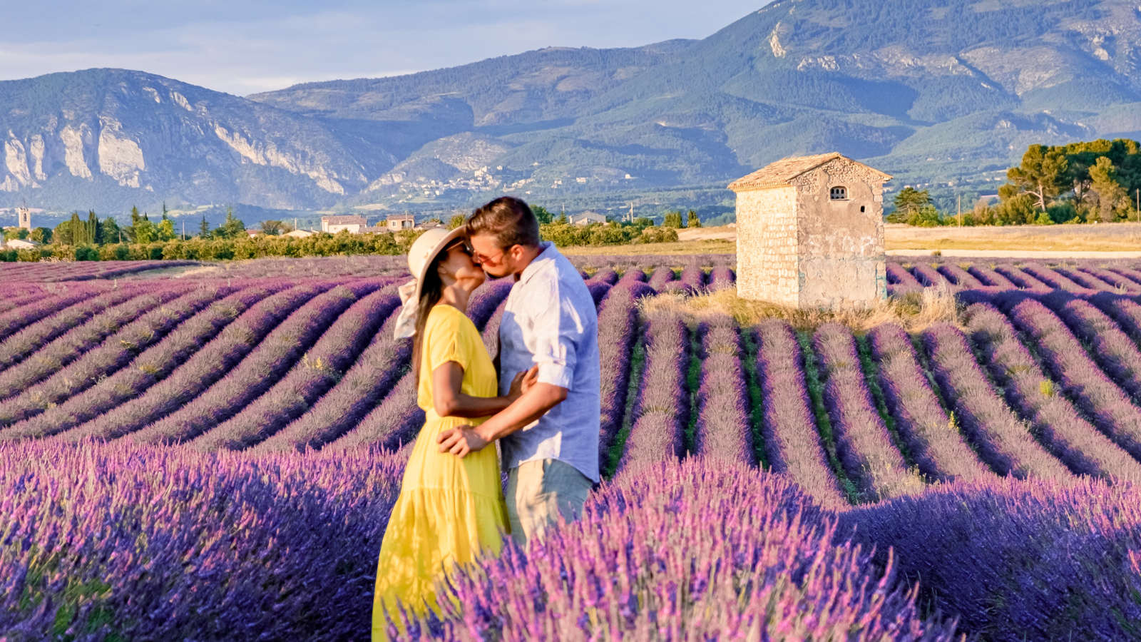 Couple embracing in blooming lavender fields with stone farmhouse in Luberon Valley, Provence, France