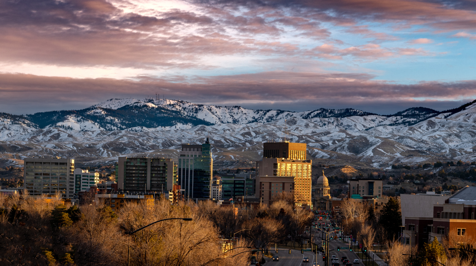 Downtown Boise skyline at sunset with snow-capped foothills and golden light in Idaho