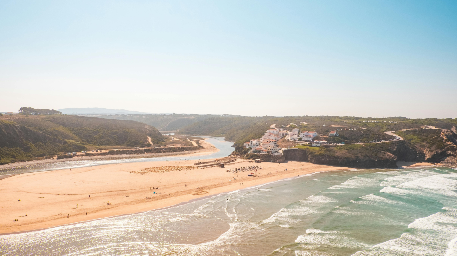 Aerial view of Portuguese coastal village with river meeting Atlantic Ocean in Alentejo region
