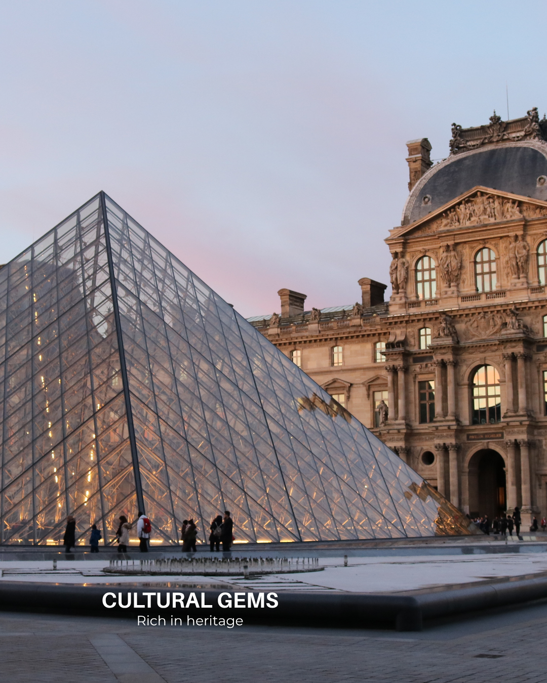 The Louvre Museum in Paris at sunset, featuring the iconic glass pyramid entrance and historic palace architecture.