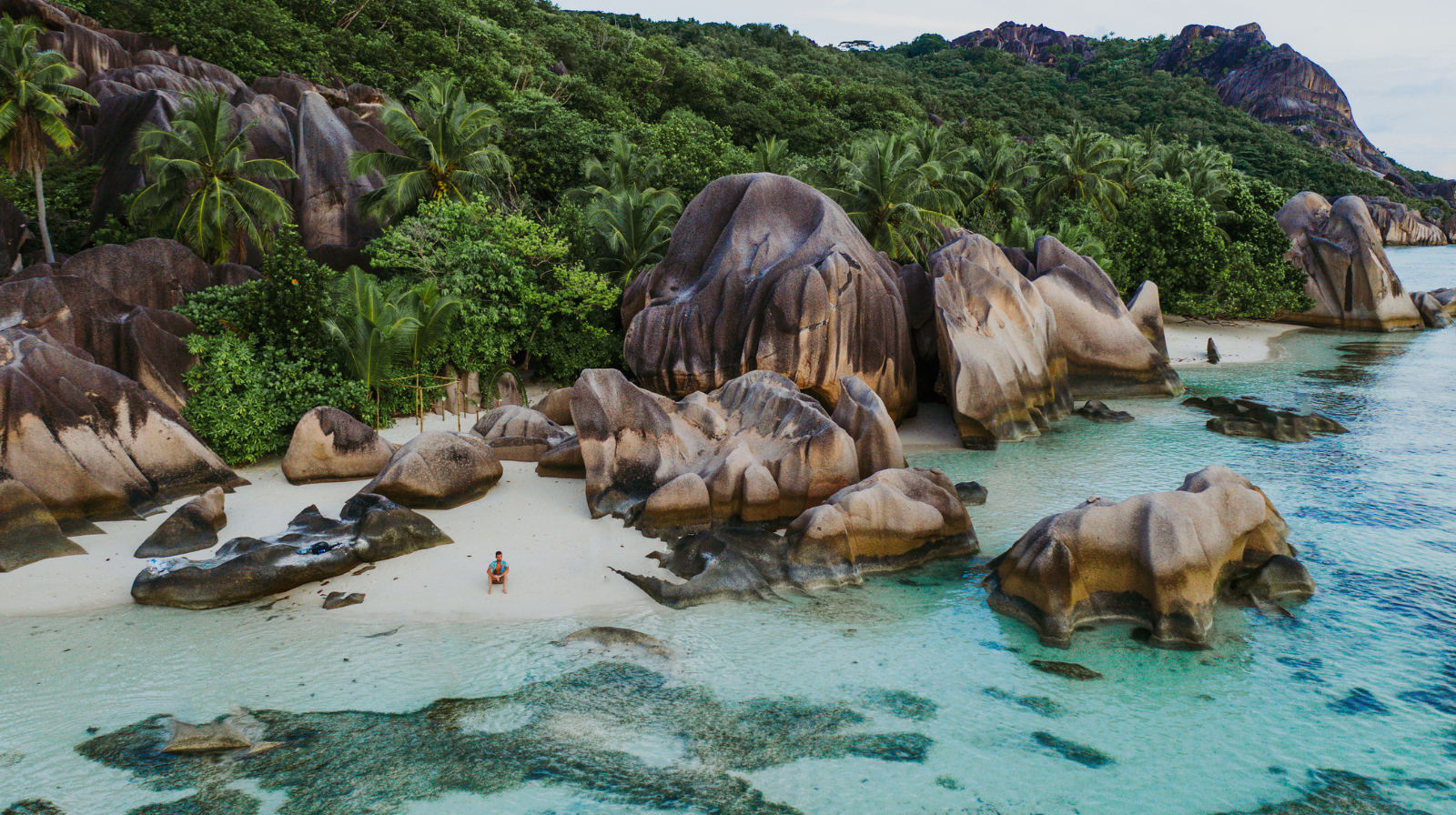 Dramatic granite boulder formations on white sand beach with turquoise water in Seychelles