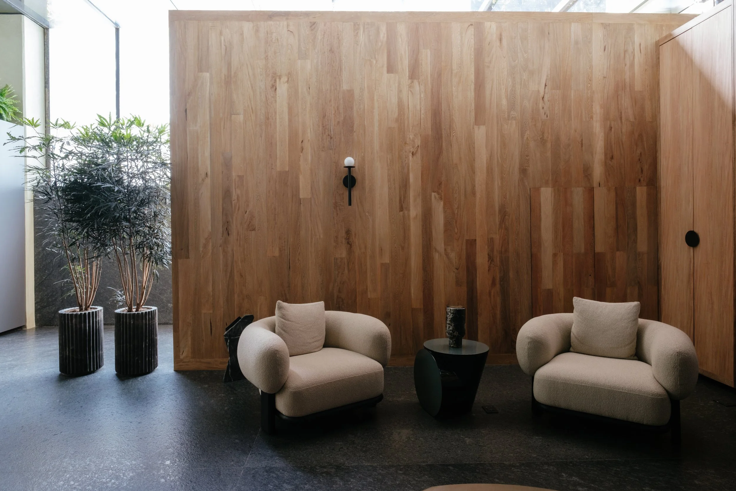 Modern lounge area at Colima 71 boutique hotel in Mexico City, Mexico, featuring contemporary armchairs, wood panel walls, and natural light—perfect for travelers seeking stylish accommodations in Roma Norte.