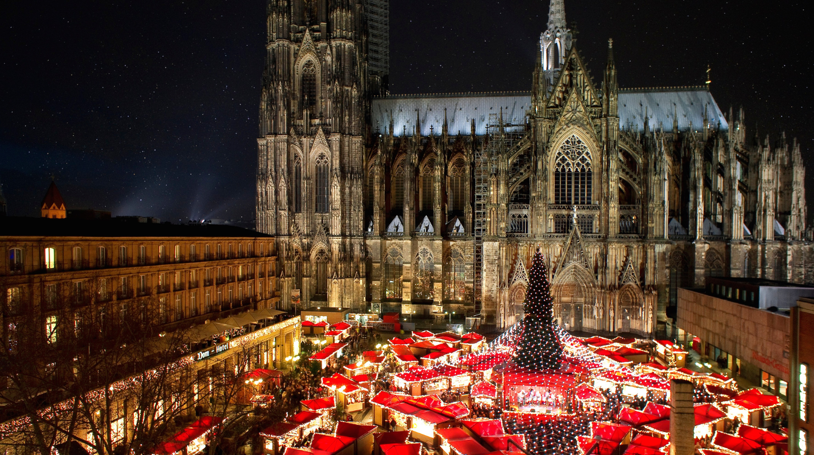 Cologne Cathedral Christmas market with red-roofed stalls and Gothic architecture at night in Germany