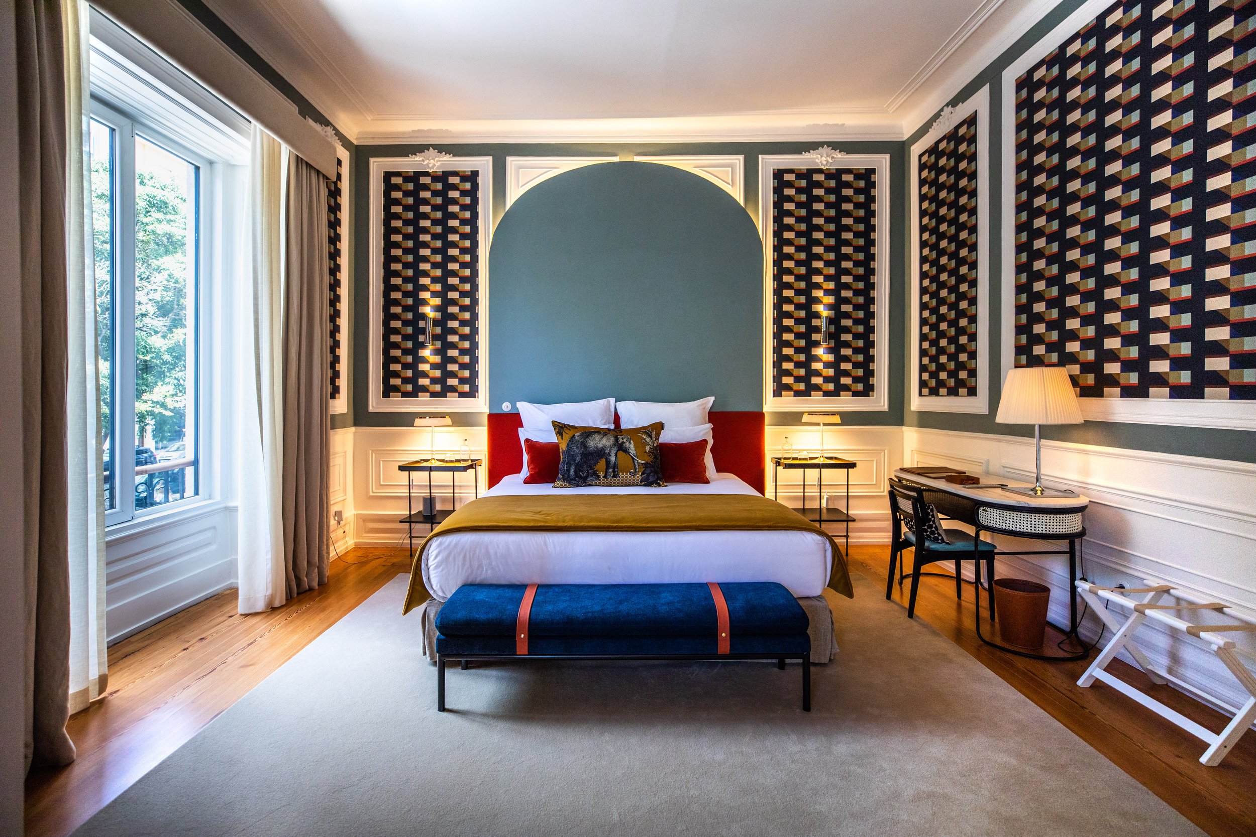 Sublime Lisboa Suite in Lisbon, Portugal—luxury hotel room with a plush king bed, geometric wall art, elegant modern furnishings, large window with natural light, and sophisticated color palette, blending contemporary design with comfort.