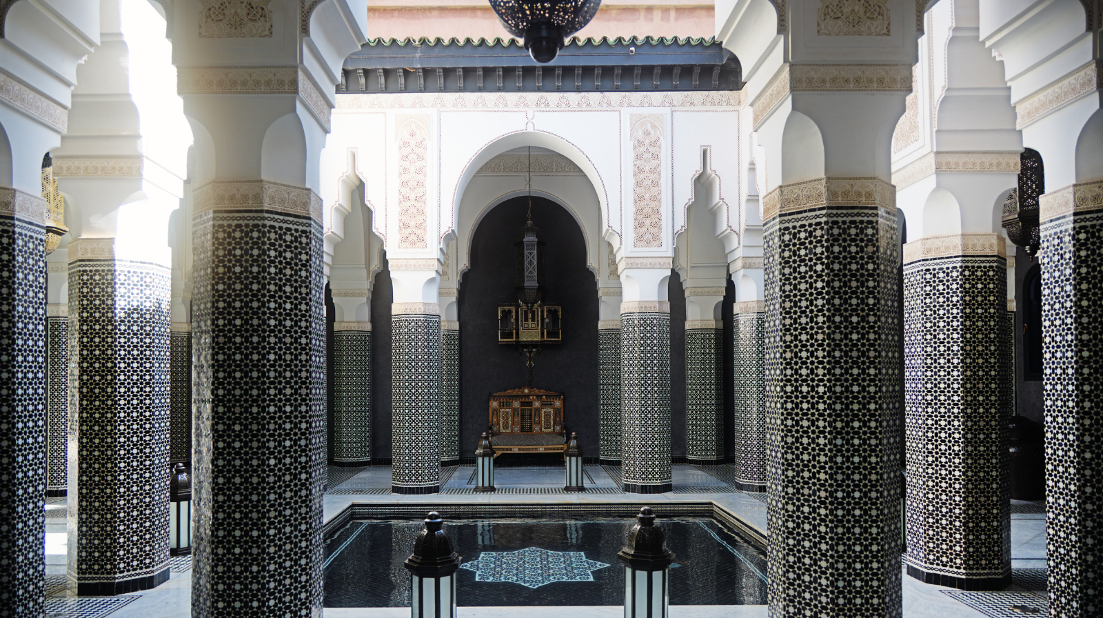 Moroccan zellige tile columns and reflecting pool in traditional riad courtyard at Selman Marrakech