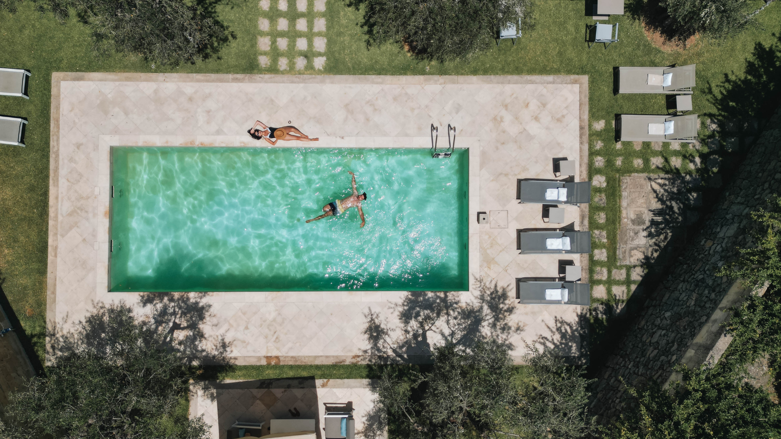 Aerial view of turquoise pool at luxury villa surrounded by olive groves in Puglia, Italy