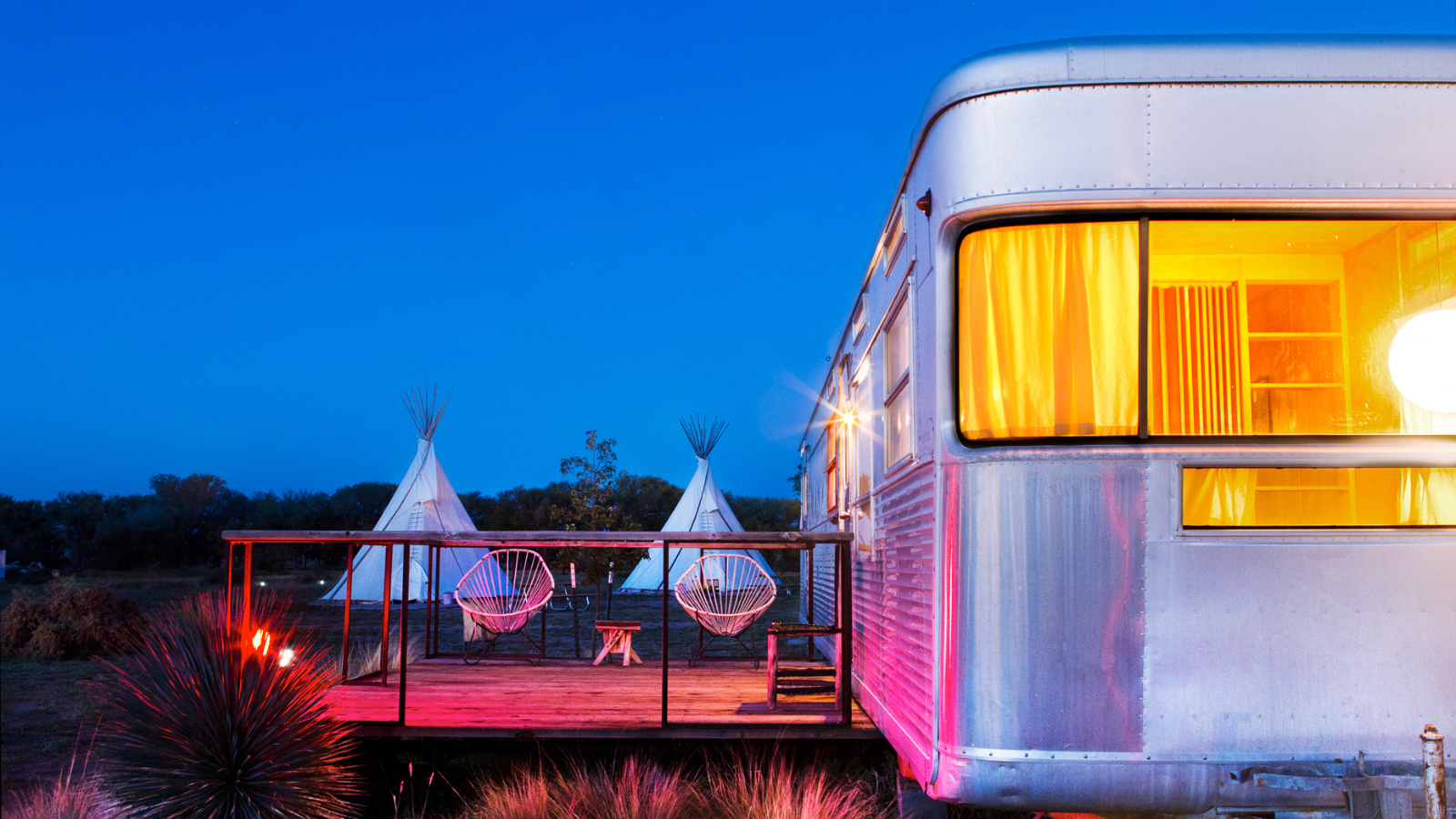 Vintage Airstream with teepees and deck at twilight in Marfa, Texas wedding venue