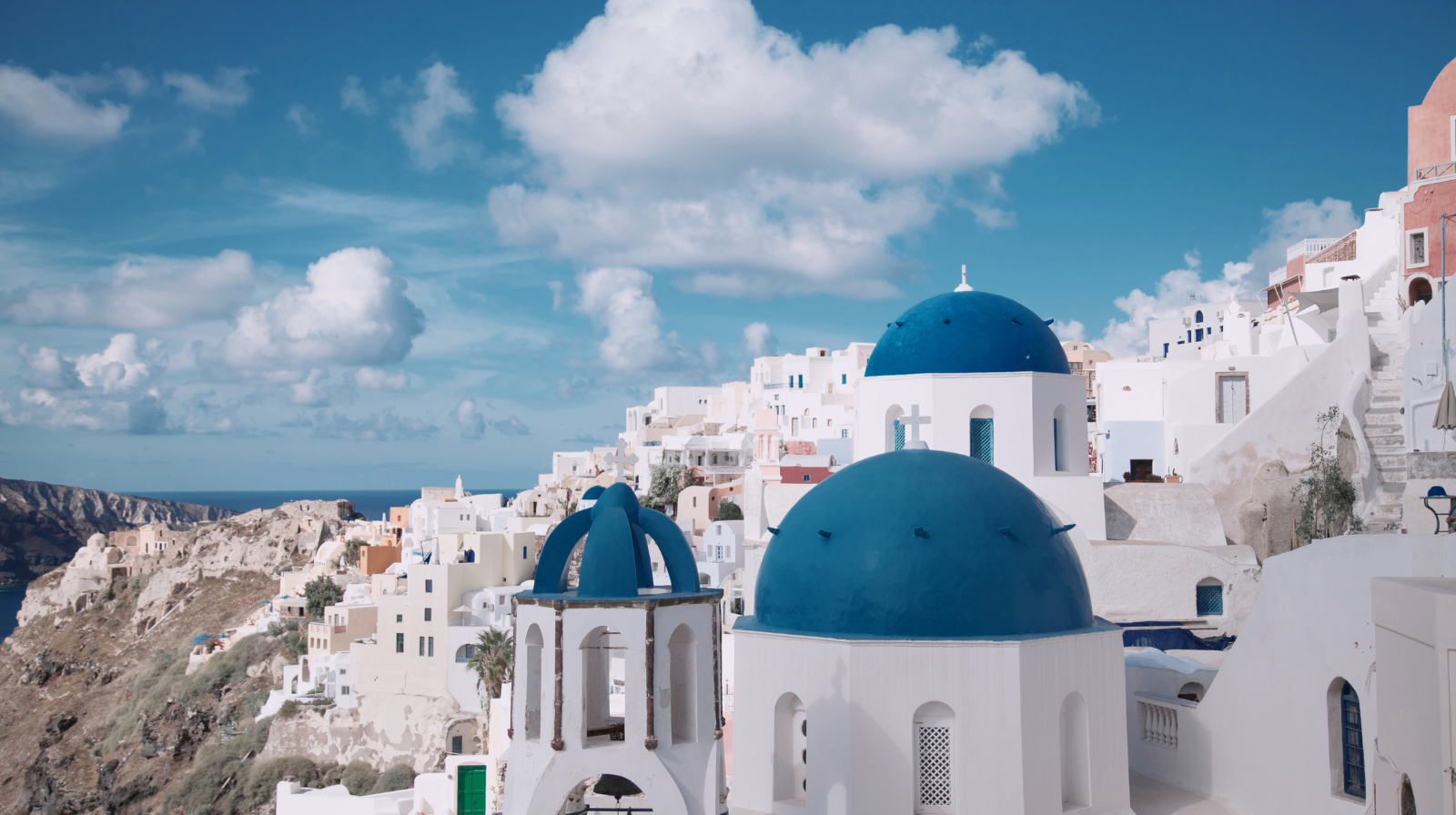 Iconic blue-domed churches overlooking the Aegean Sea in Oia, Santorini, Greece