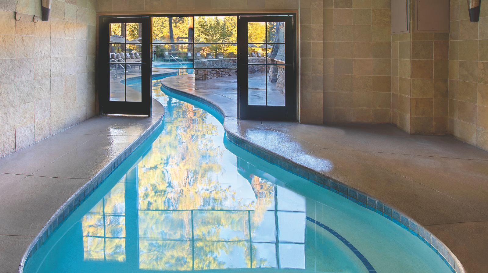 Indoor heated pool at Hyatt Regency Lake Tahoe with windows overlooking outdoor pools and mountains