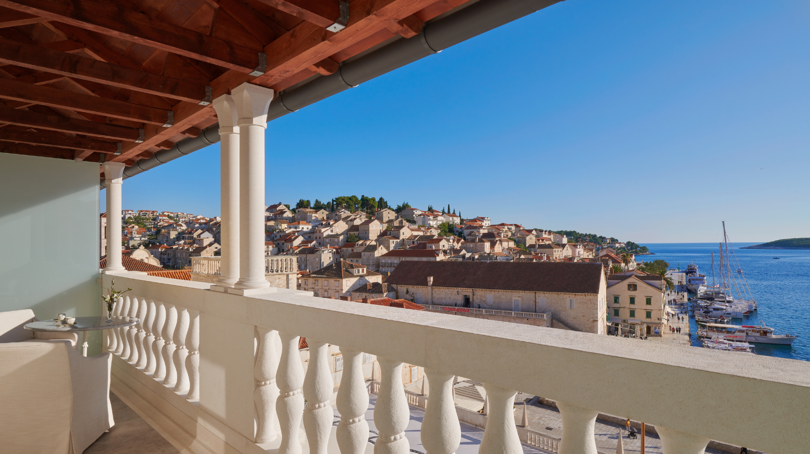 Balcony at Palace Elizabeth Hvar Hotel in Hvar, Croatia, overlooking historic town rooftops, harbor, and Adriatic Sea under clear blue sky.