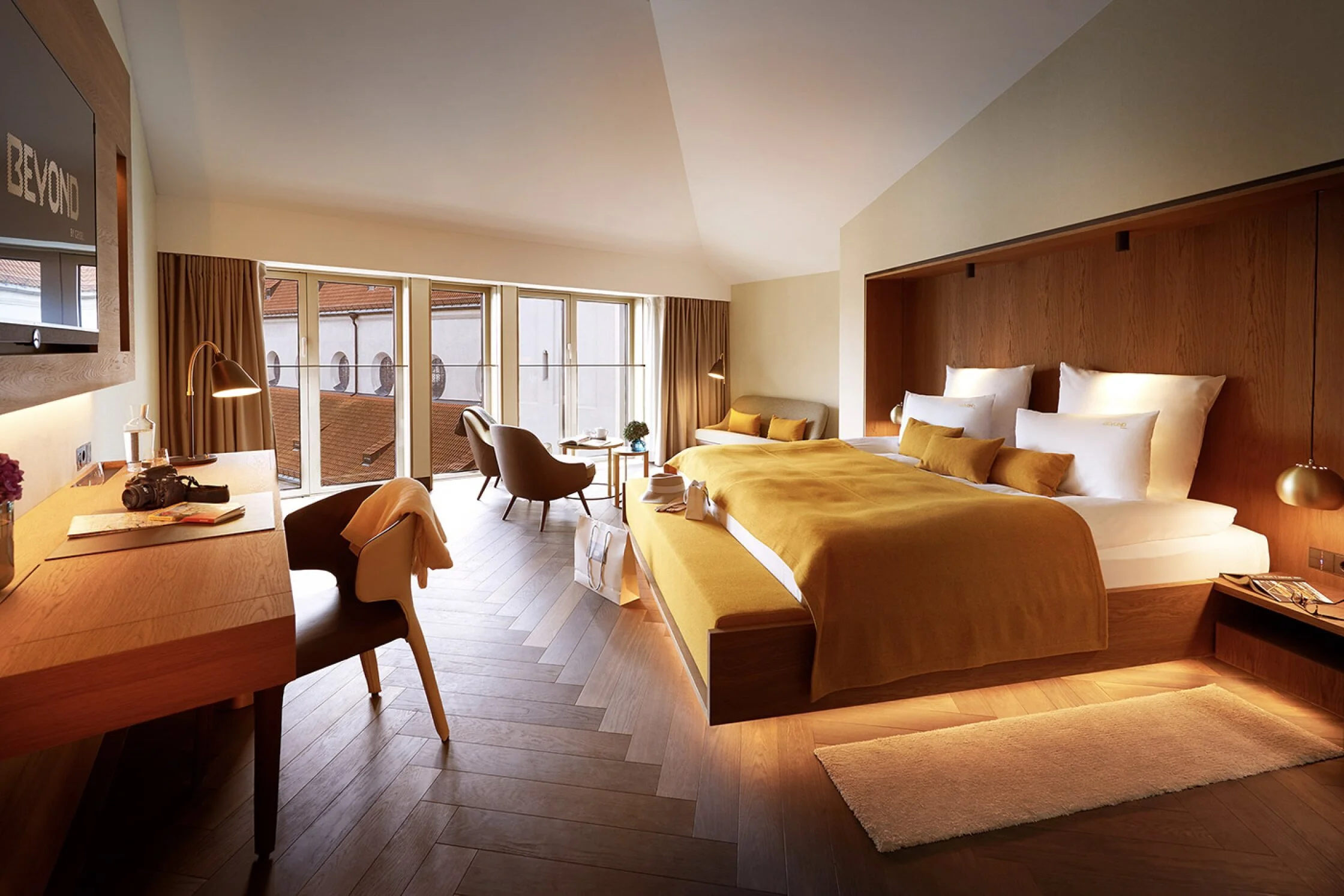 Spacious luxury hotel room at BEYOND by Geisel in Munich, Germany, featuring modern design, king-size bed, floor-to-ceiling windows, and city views—ideal for travelers seeking upscale accommodations in central Munich.