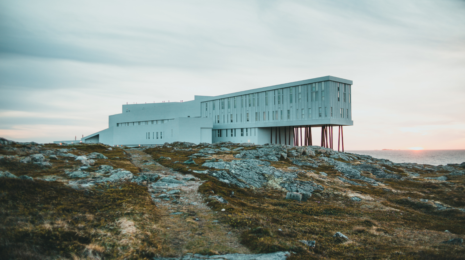 Contemporary Fogo Island Inn on stilts overlooking rocky coastline and Atlantic Ocean in Newfoundland, Canada
