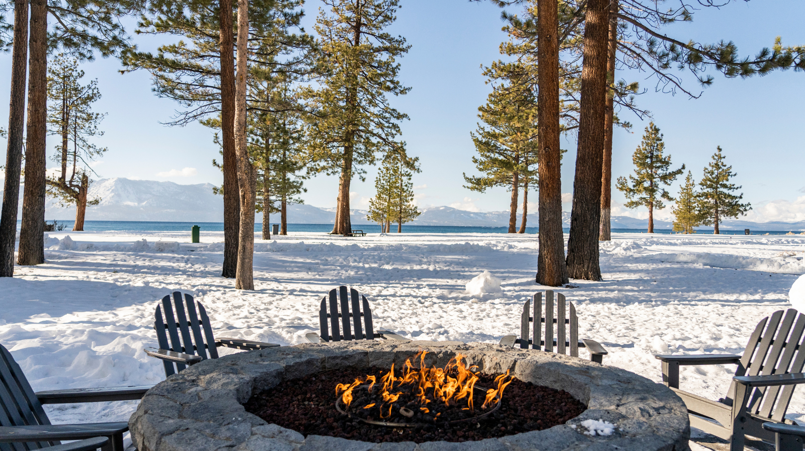Edgewood Tahoe Hotel lakefront fire pit with Adirondack chairs overlooking snow-covered Lake Tahoe mountains