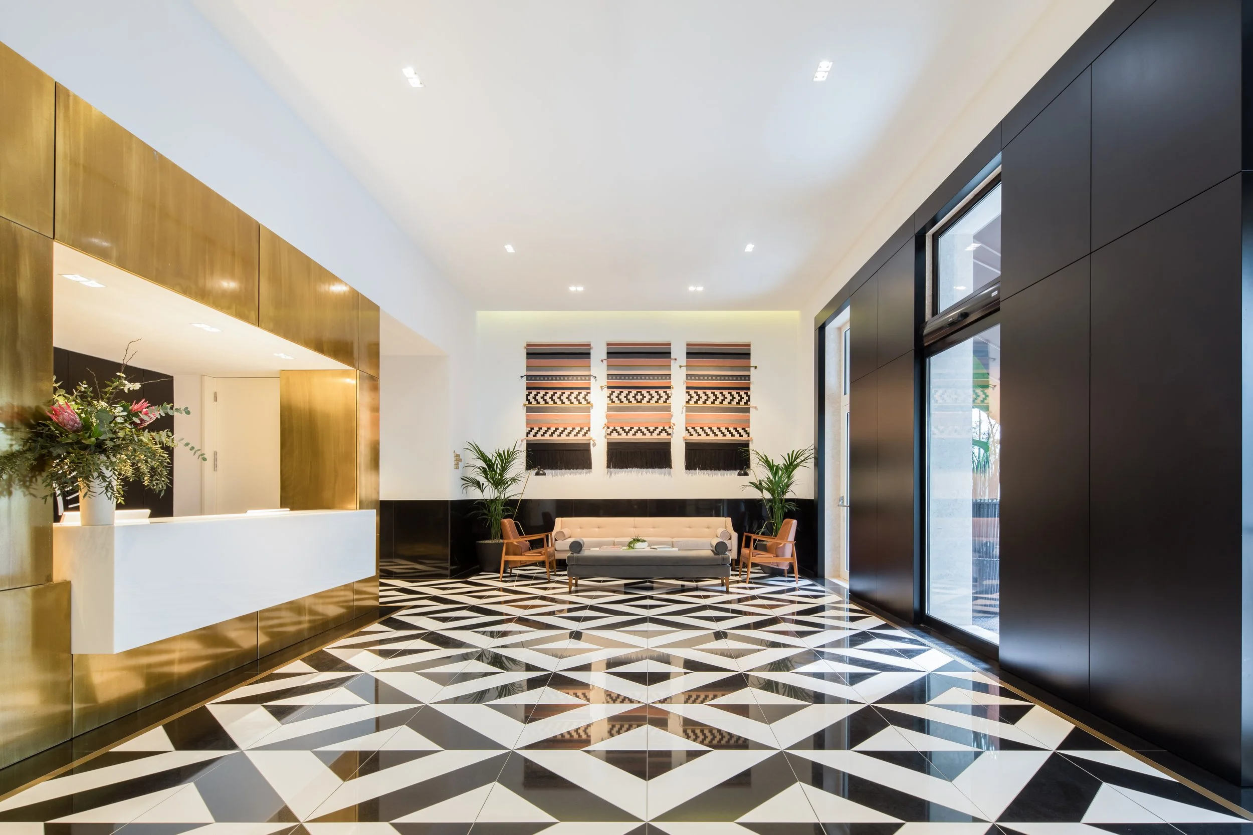 The Lumiares Hotel lobby in Bairro Alto, Lisbon, Portugal—modern luxury design with geometric black-and-white floor, gold accents, and contemporary seating, ideal for travelers seeking stylish boutique accommodation.