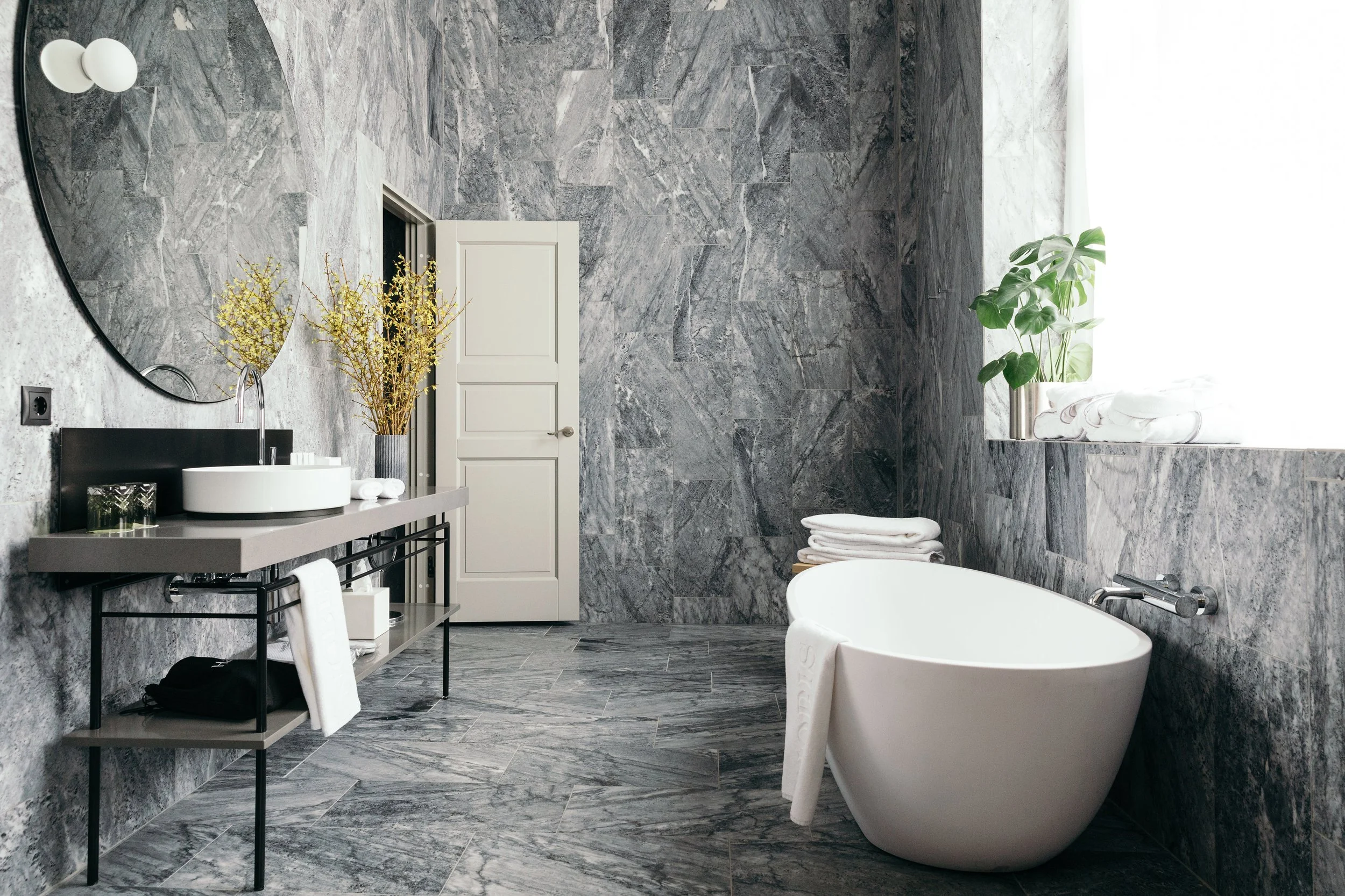Scandinavian luxury bathroom at Nobis Hotel Copenhagen in Denmark, featuring marble walls, freestanding soaking tub, and modern minimalist design—ideal for travelers seeking upscale accommodations in central Copenhagen.