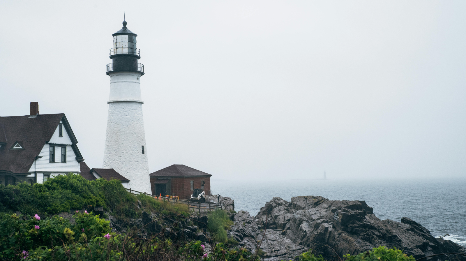 Portland Head Light lighthouse on rocky Maine coastline with foggy ocean in winter New England