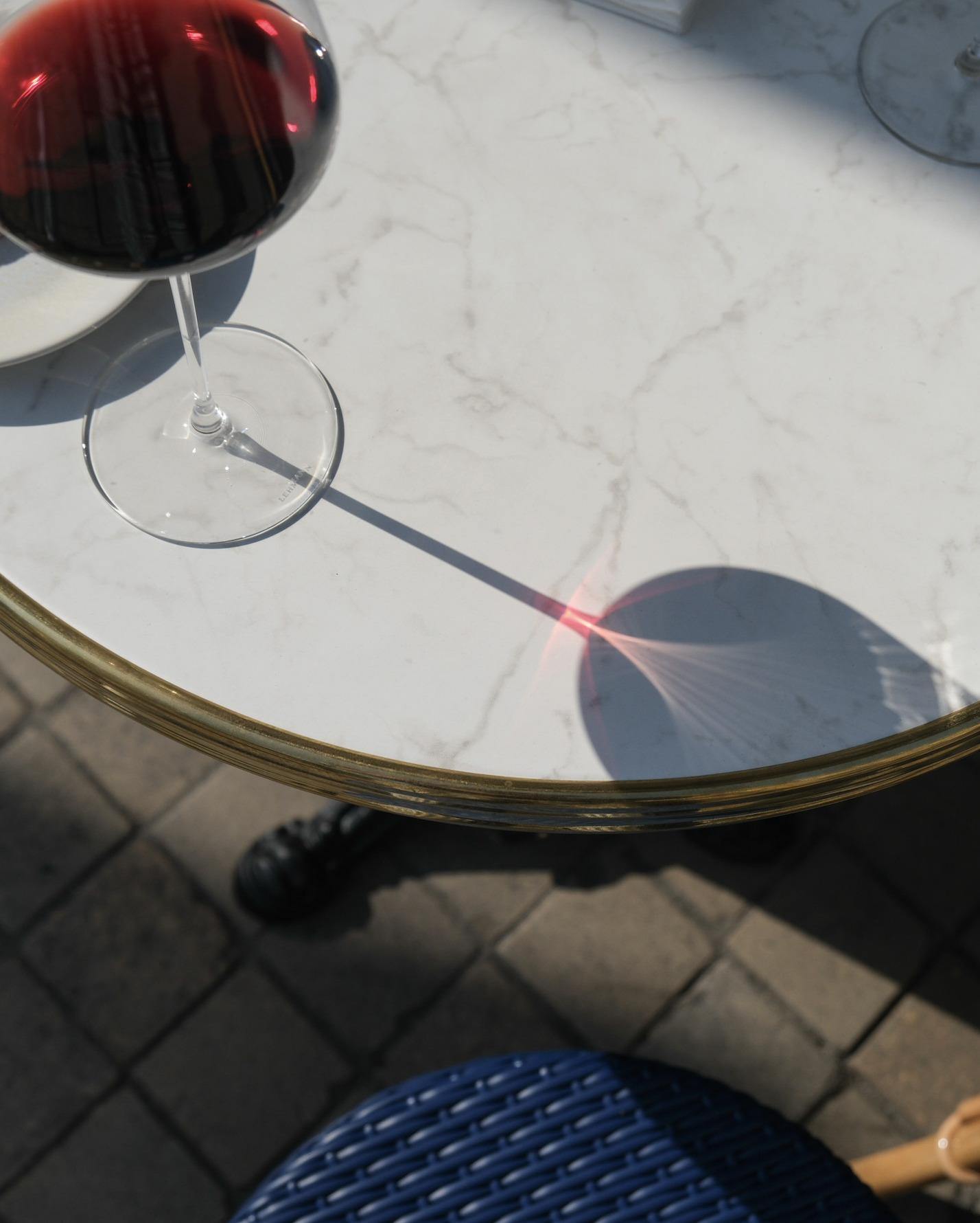 Verre de vin rouge sur une table en marbre blanc avec une ombre de rayon laser rouge.