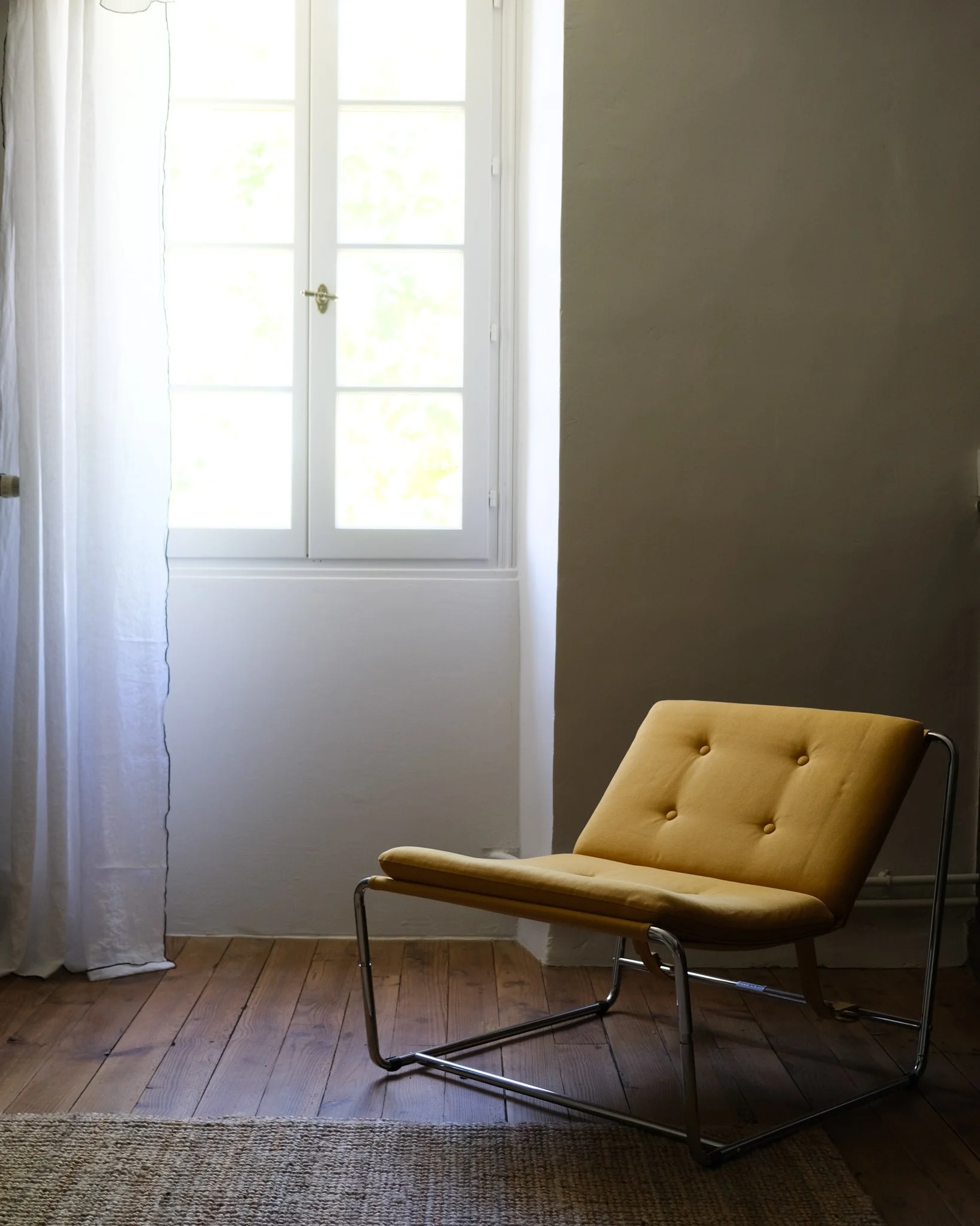 Une pièce lumineuse avec une fenêtre et un fauteuil jaune en cuir dans le coin.