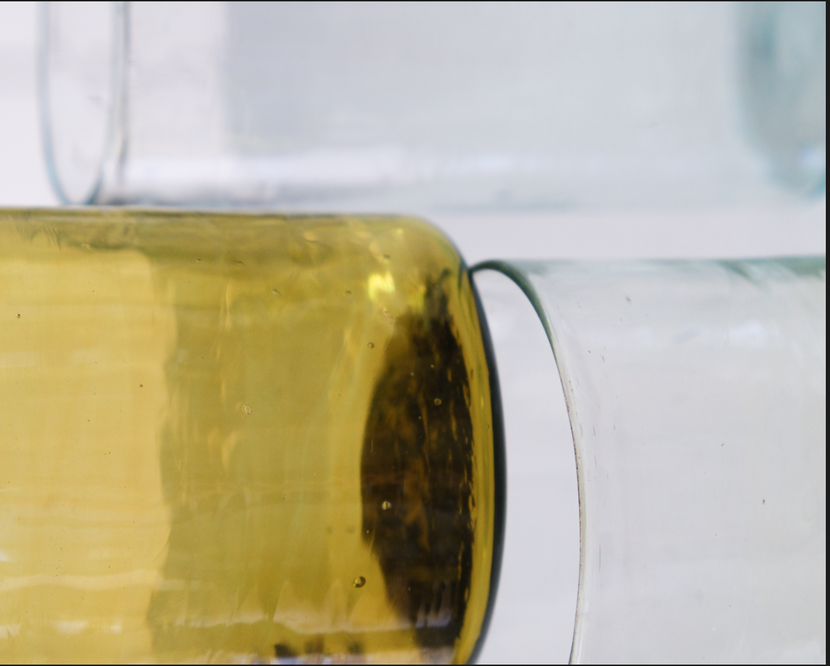 Deux verres en verre, un rempli d'une boisson jaune, posé l'un sur l'autre.