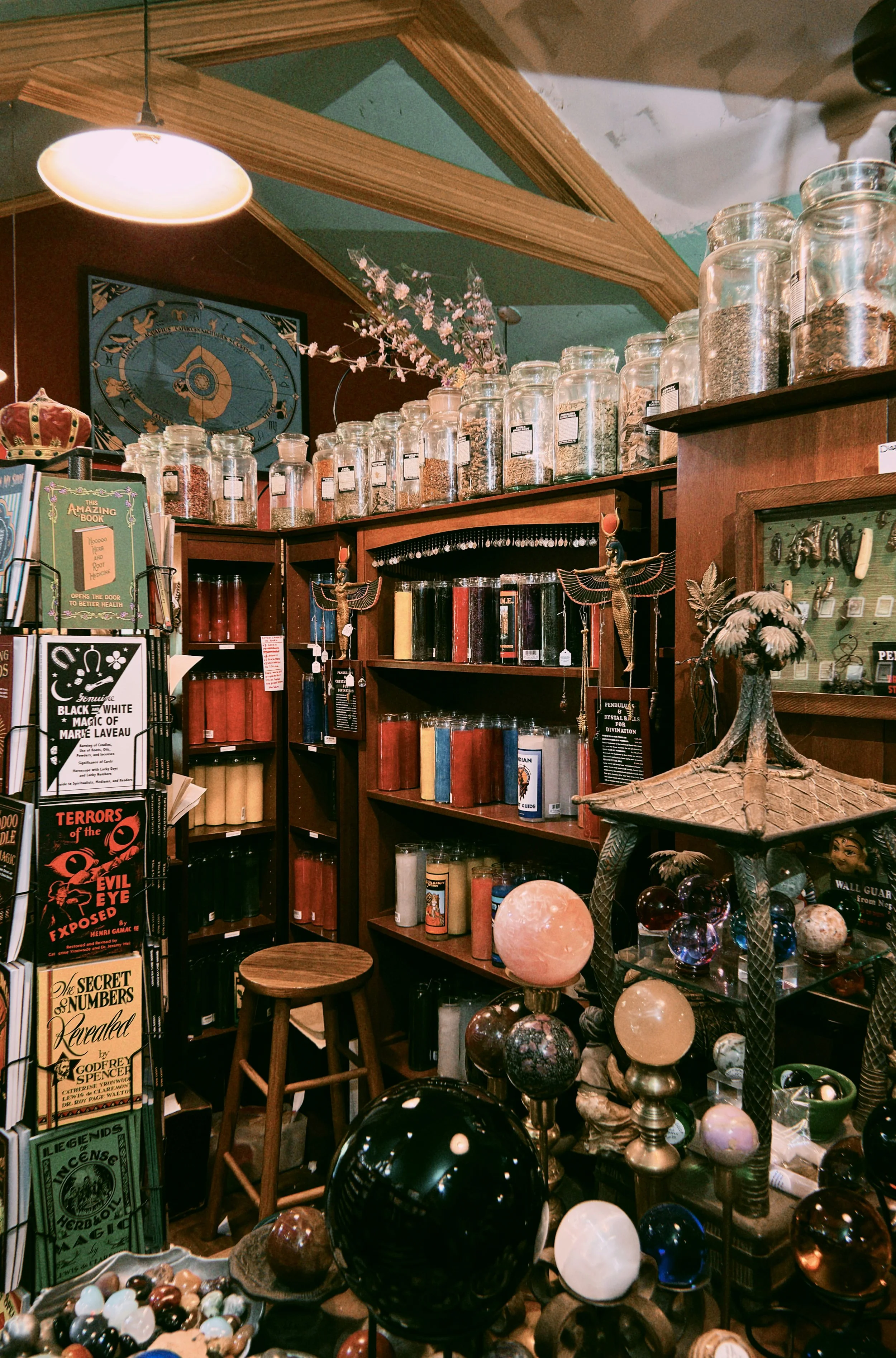 A store display with shelves of jars, books, globes, and crystal balls, featuring decorative items and signs in the background.