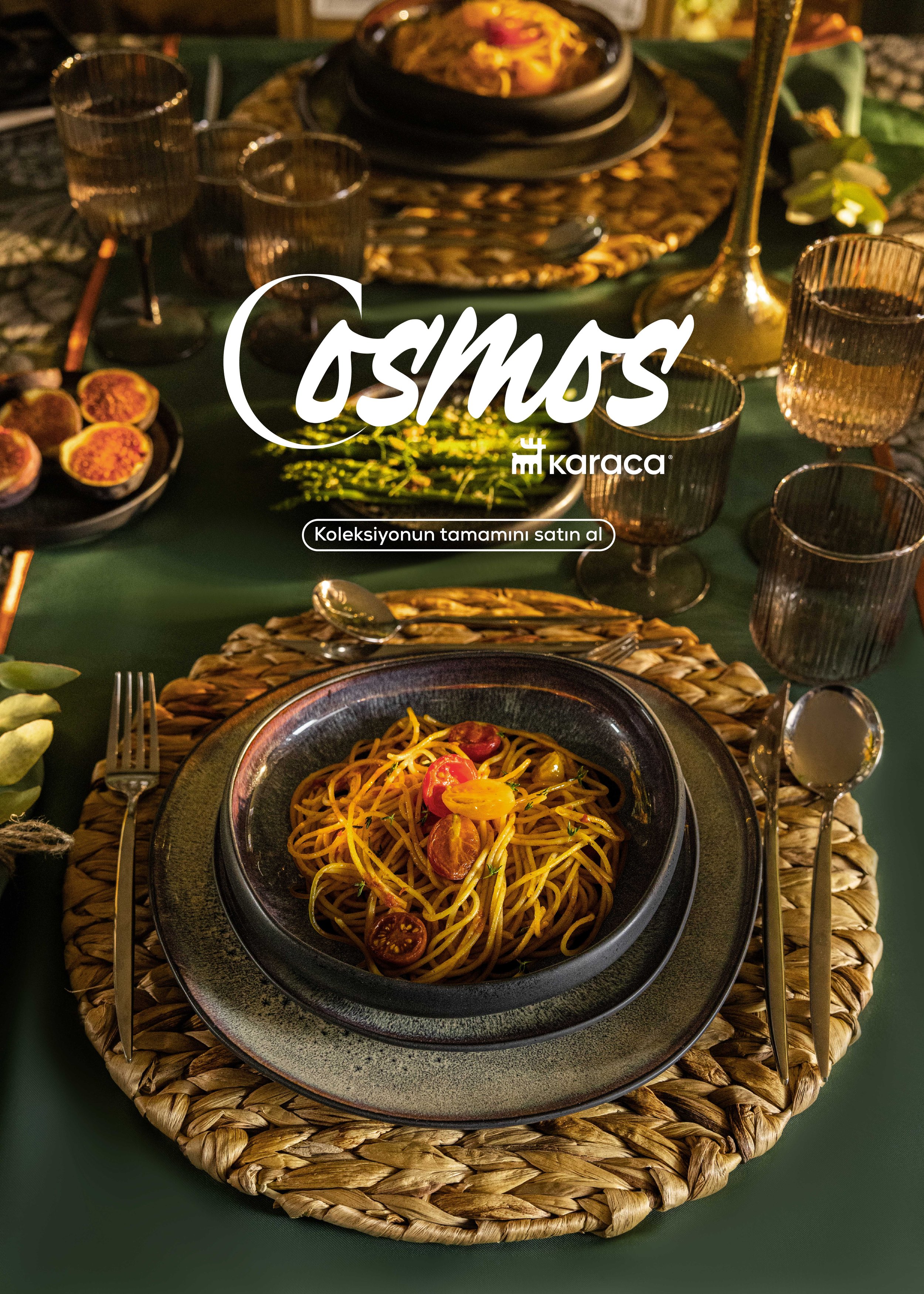 A table setting with a bowl of spaghetti topped with cherry tomatoes in the foreground, surrounded by glassware, silverware, and other dishes, with a dark green tablecloth and woven placemats.