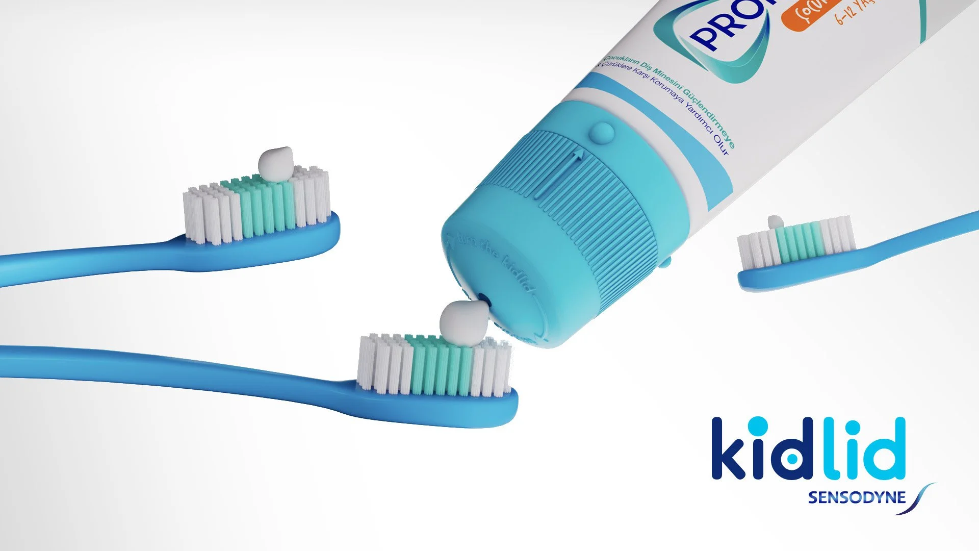 Tube of KidLid Sensodyne toothpaste with three toothbrushes, each with a small amount of white, green, and blue toothpaste on the bristles, set against a white background.