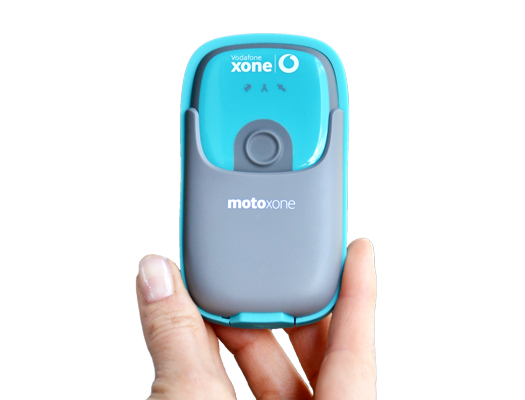 Person holding a small teal rectangular tracking device with Vodafone Xone branding, against a clear background.