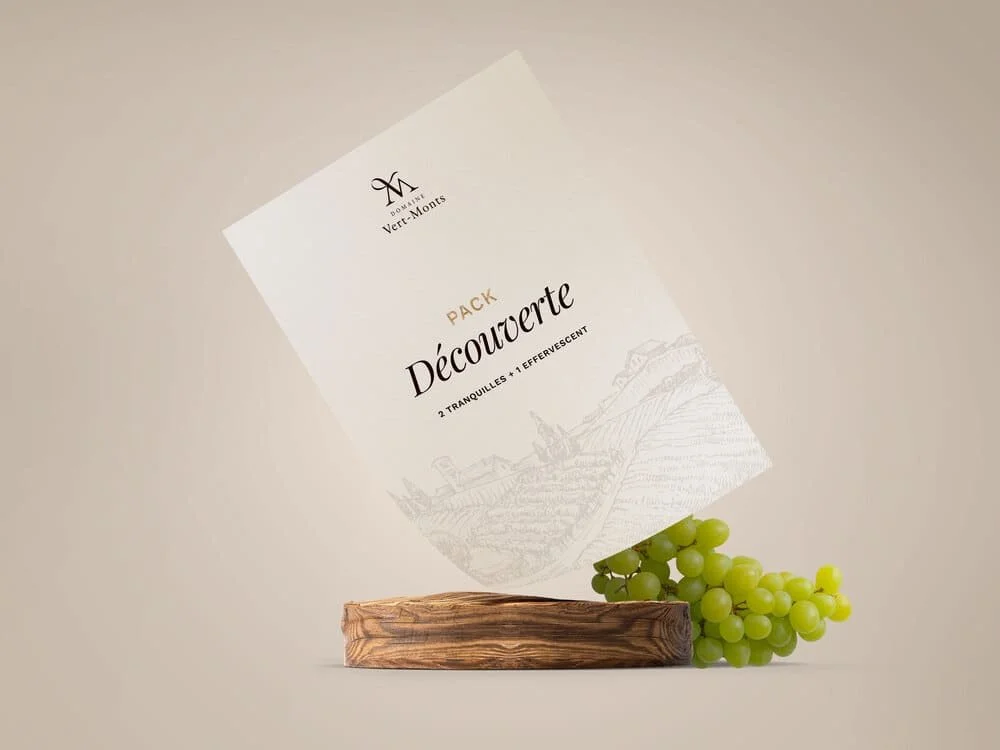 Un paquet de Thés Domaine Vert-Monts, nommé 'Découverte', posé sur une surface en bois avec un bouquet de raisins verts à côté. Domaine Vert Monts, vignoble belge à Ath (Pays Vert) — cépages interspécifiques, préventes ouvertes.