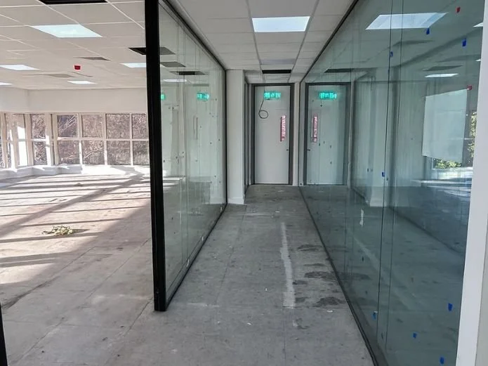 Empty indoor space with glass walls and a door, under construction or renovation.