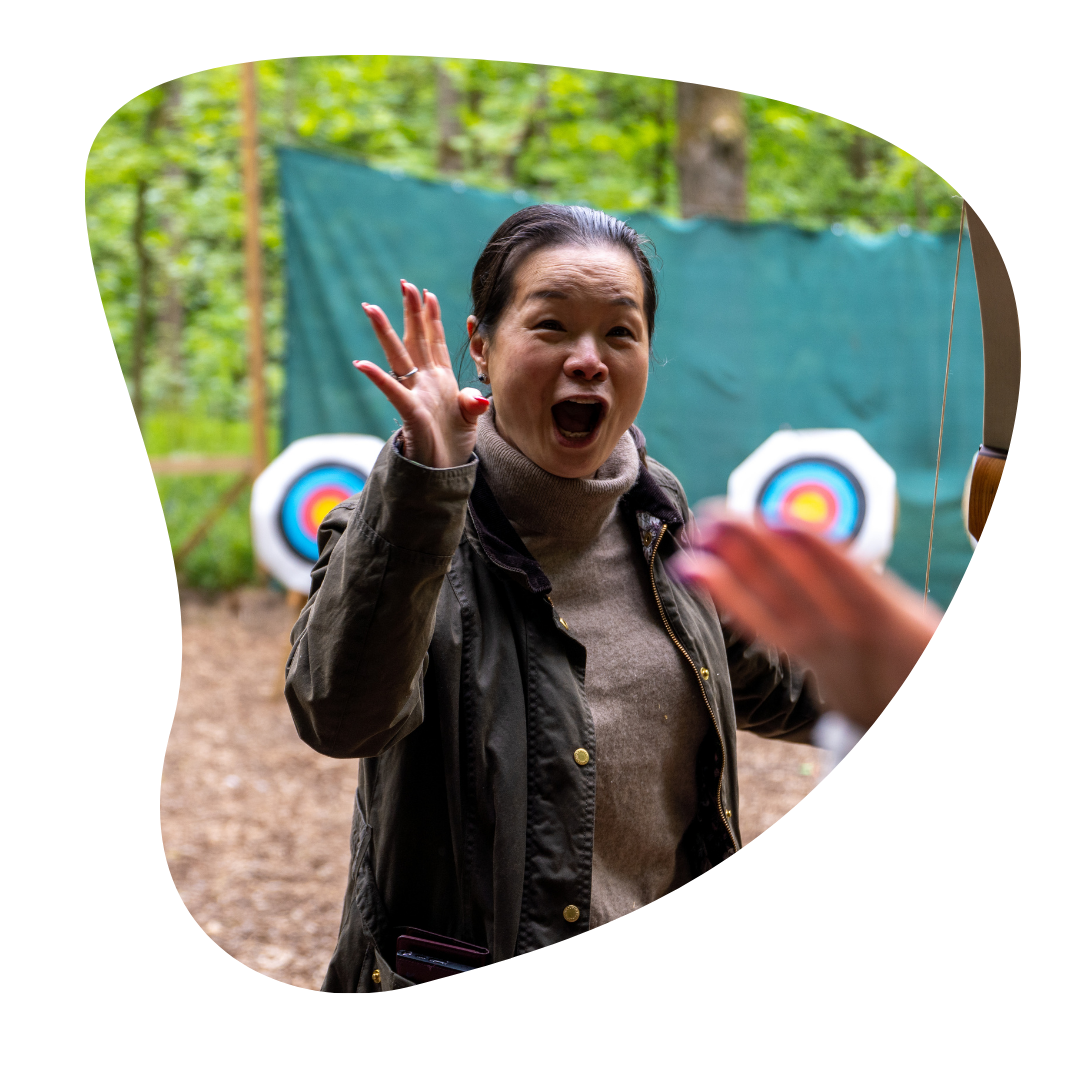 Woman at an archery range reacting with excitement, with targets visible in the background
