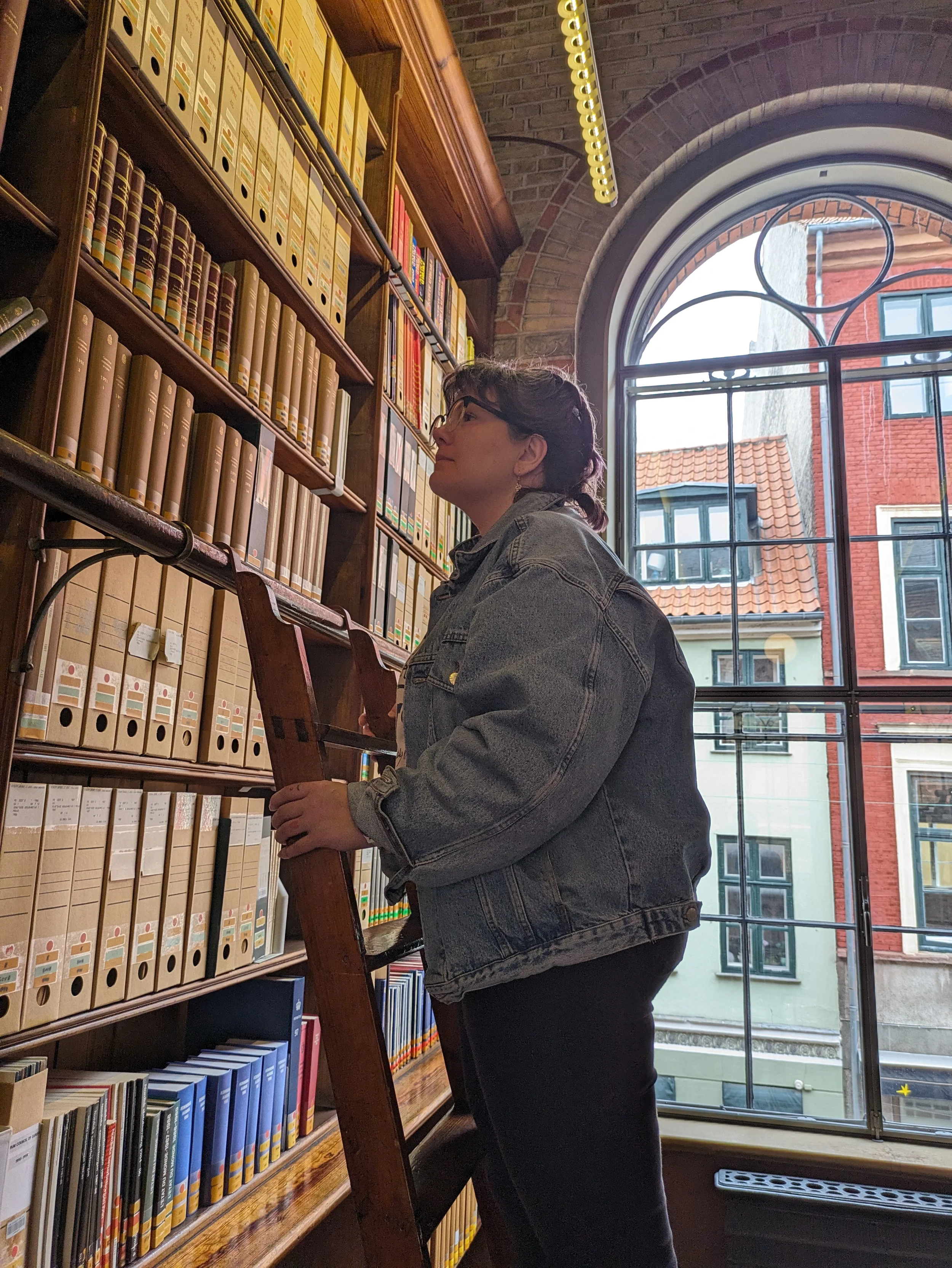 amélie hennequin, french SEO translator, jean jacket, in an ancient library