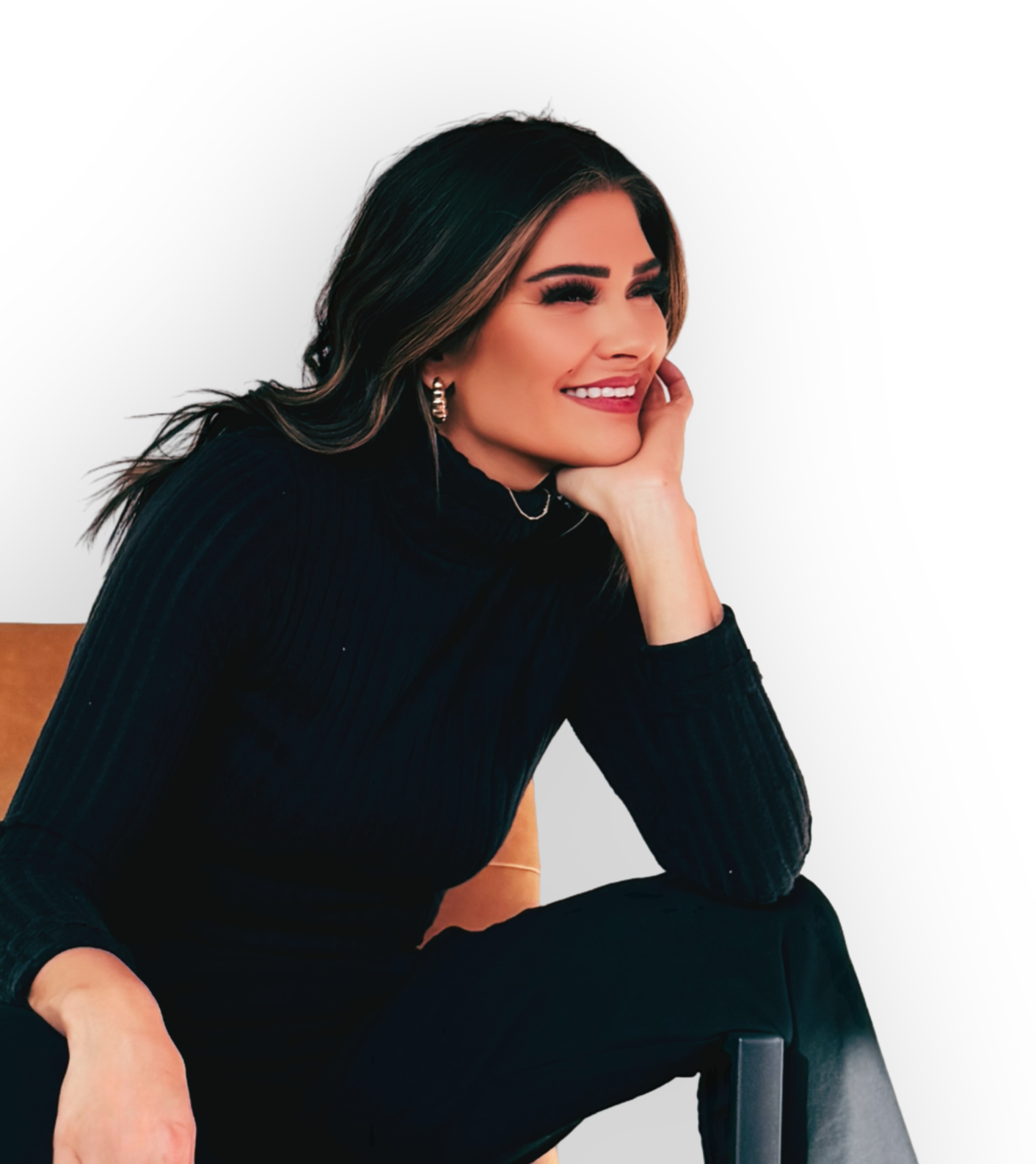 Woman with long dark hair and earrings sitting posed against a black background, smiling with her hand resting on her face, dressed in a black turtleneck.