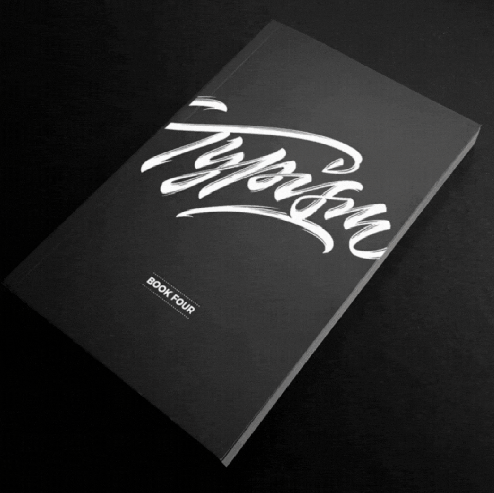 A black on black book with white cursive text that reads "Black Book."