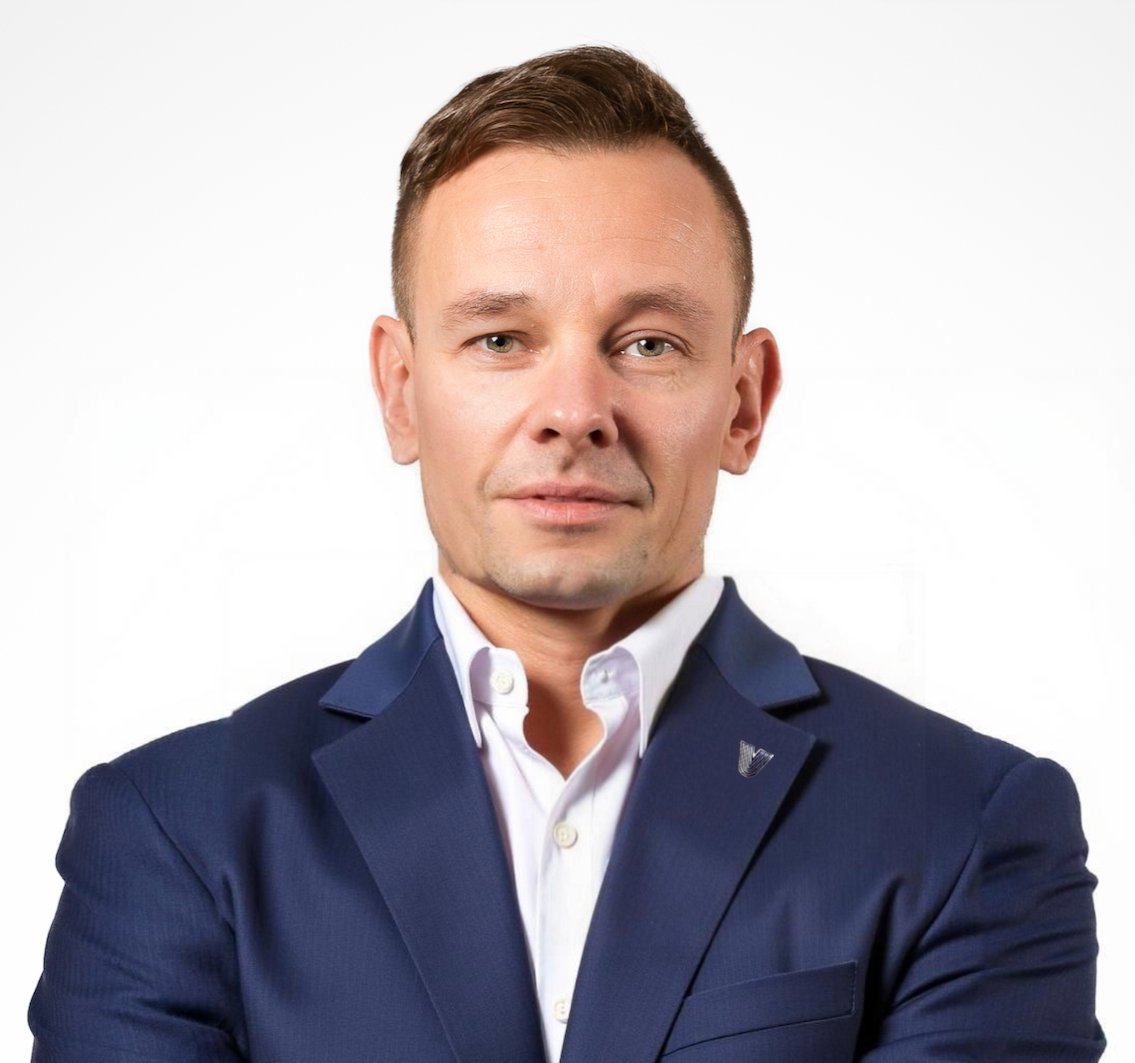 Headshot of a man with short brown hair in a navy suit, white shirt, against a white background.