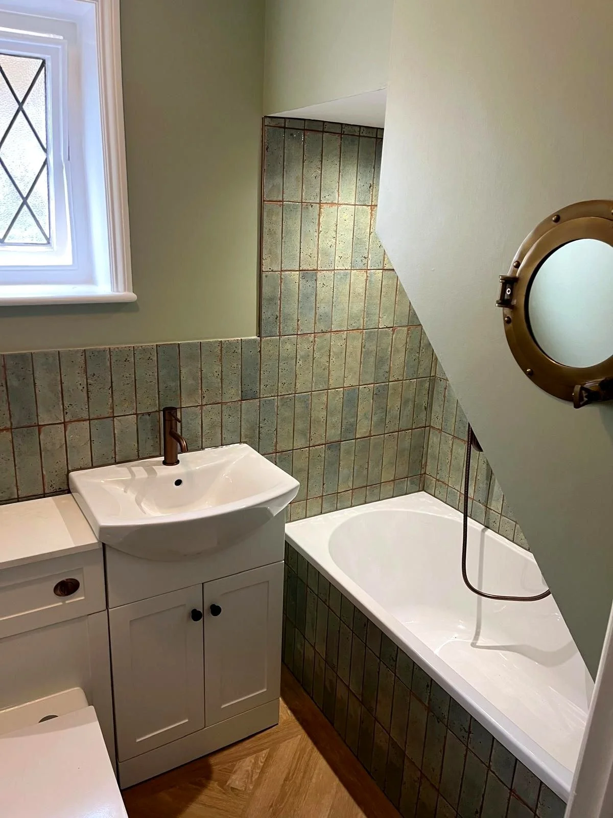 Traditional bathroom featuring fitted bath, vanity unit and tiled splashback in a compact, well-finished space.