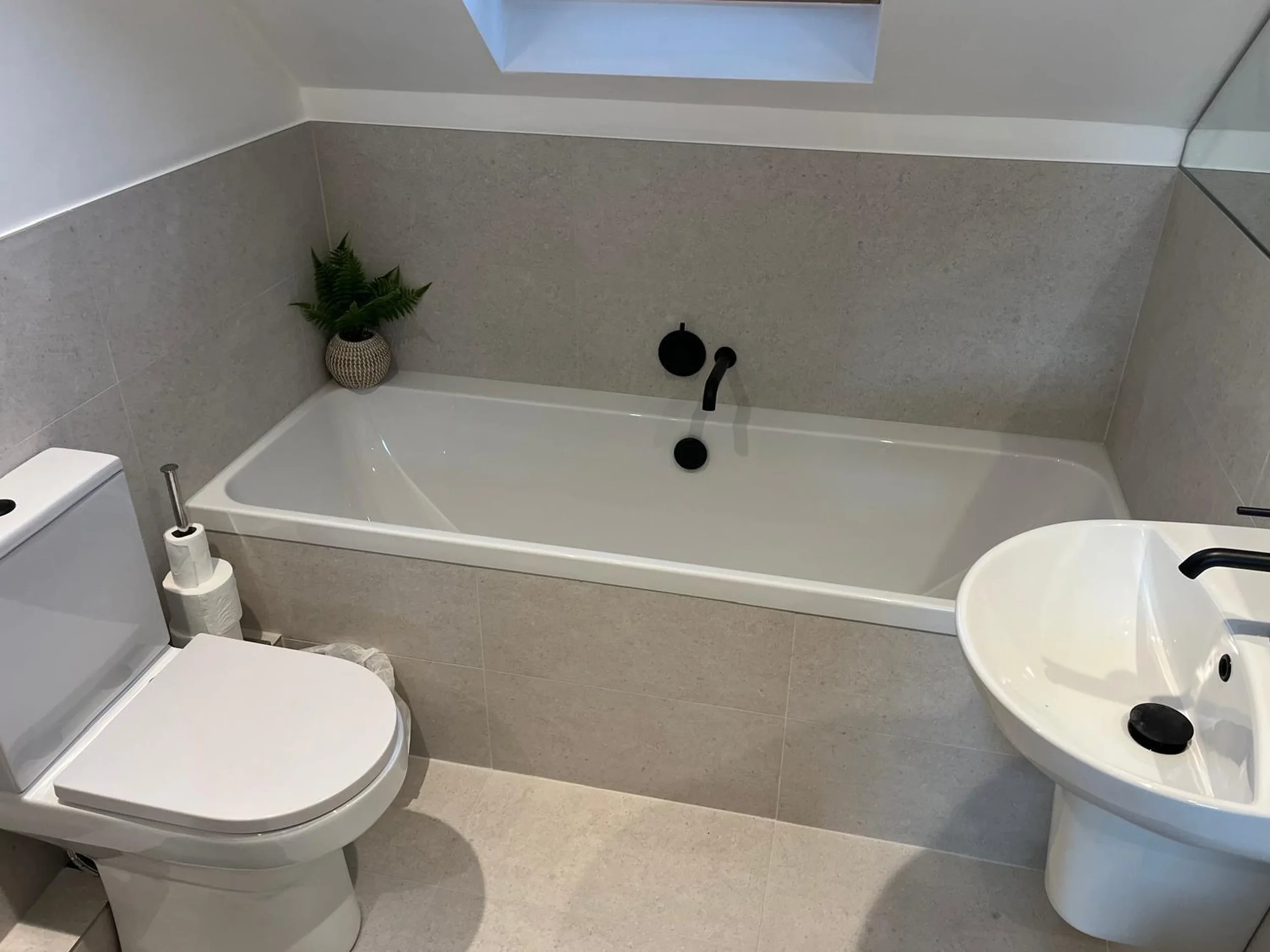Built-in bath with neutral tiling and skylight in a finished Brighton bathroom
