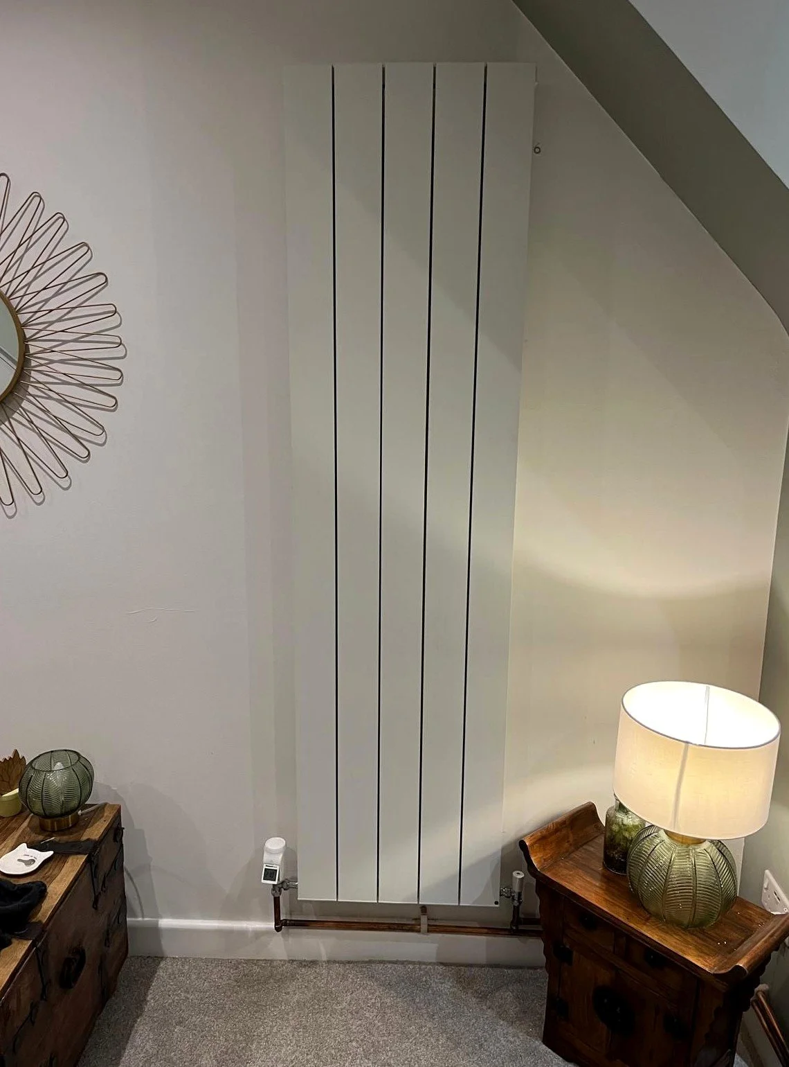 Vertical designer radiator installed neatly in a modern interior with clean pipework and finish