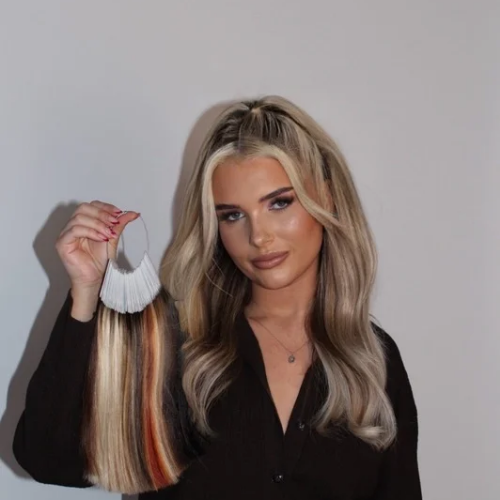 Livona London founder wearing livona hair extensiona, holding a hair extension sample with multiple color strands.