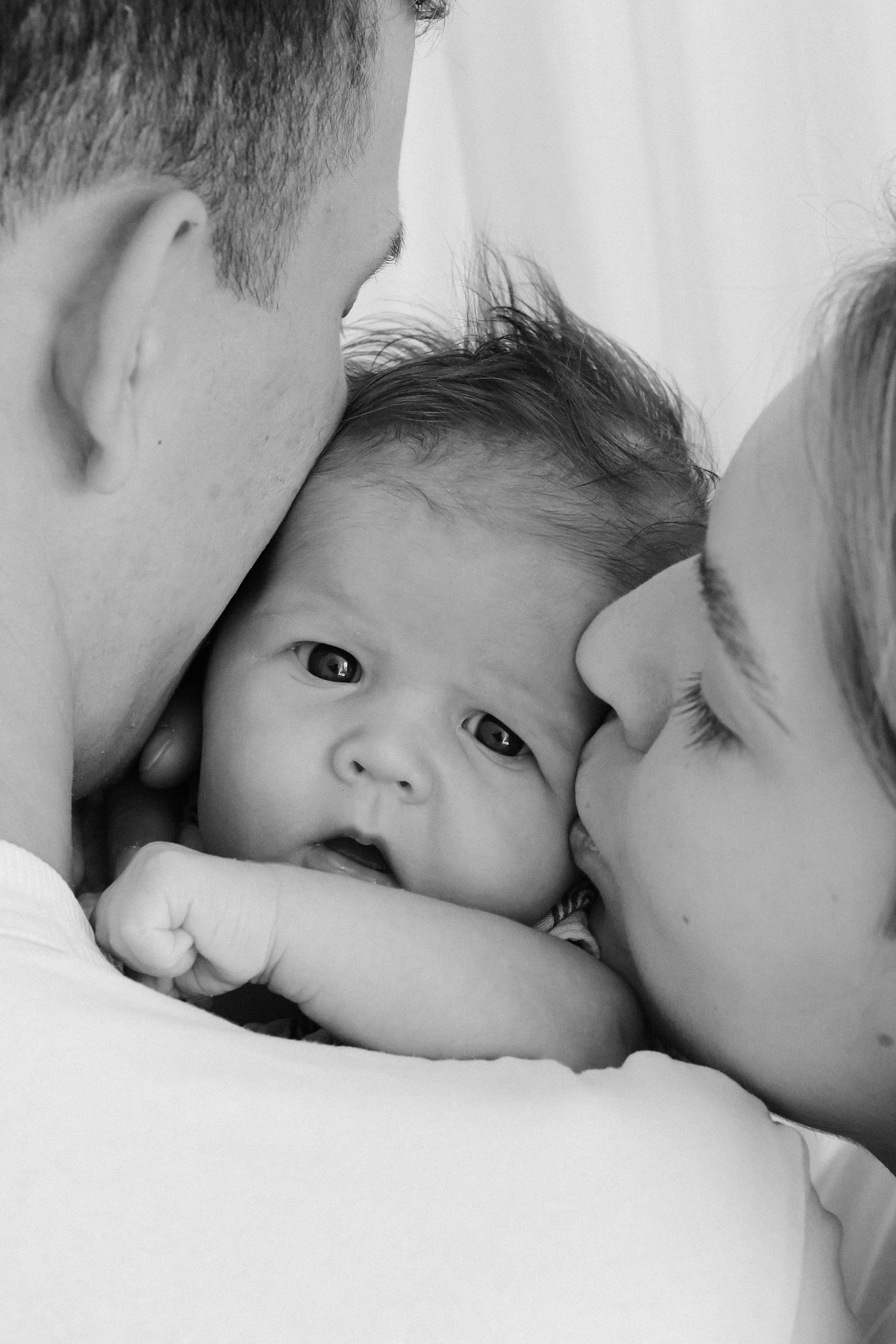 parents kissing infant