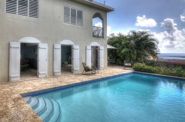 Large outdoor swimming pool area with lounge chairs and ocean views.
