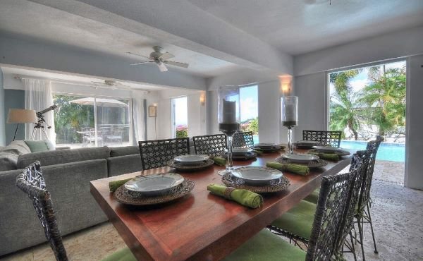 Dining room with a large wooden table and seating for 6 people and views to the pool.