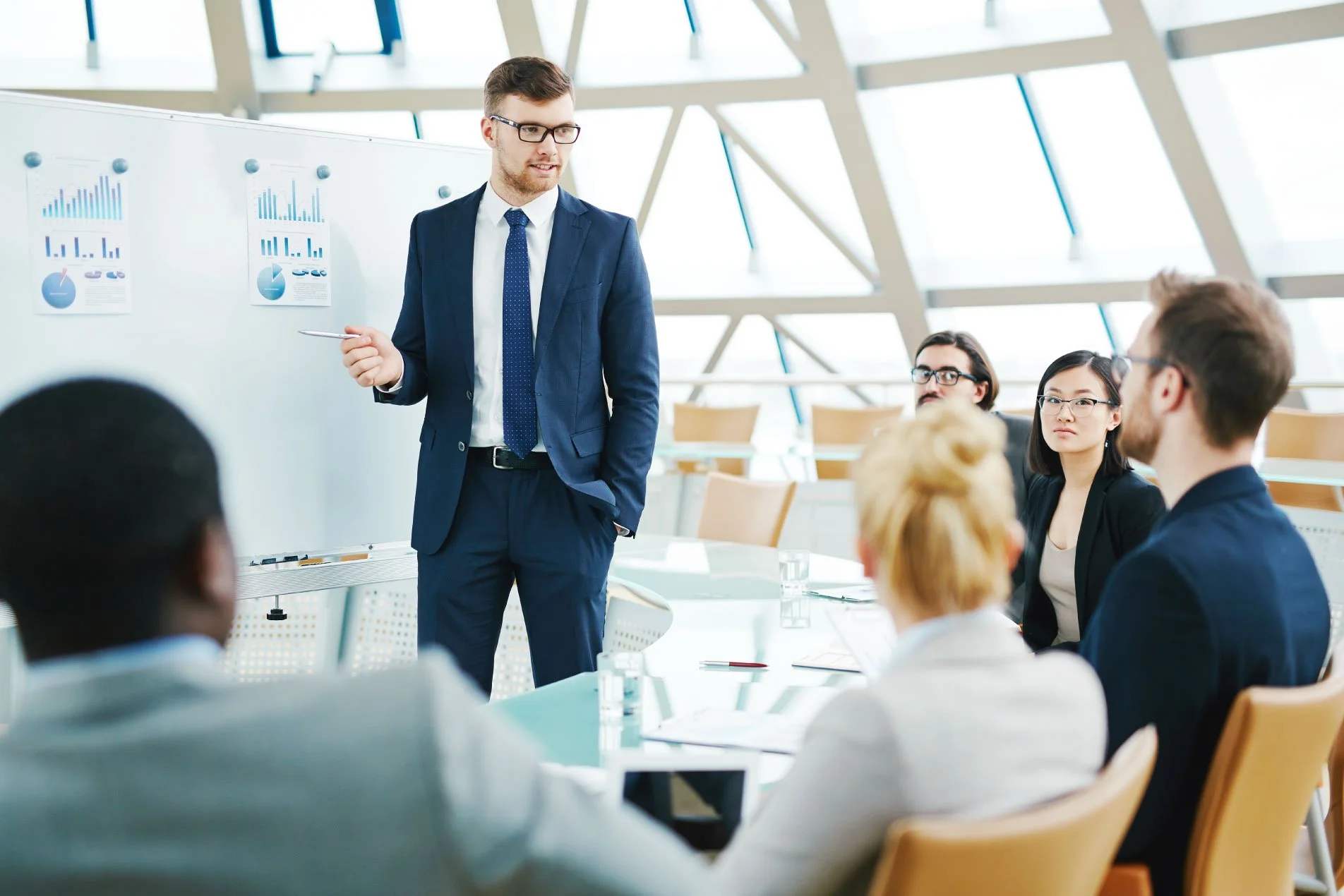 Young male manager conducting a meeting and pointing to a chart.