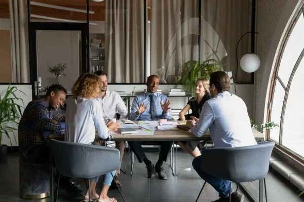 Team of colleagues sitting around a conference table engaged in a meeting led by a male executive